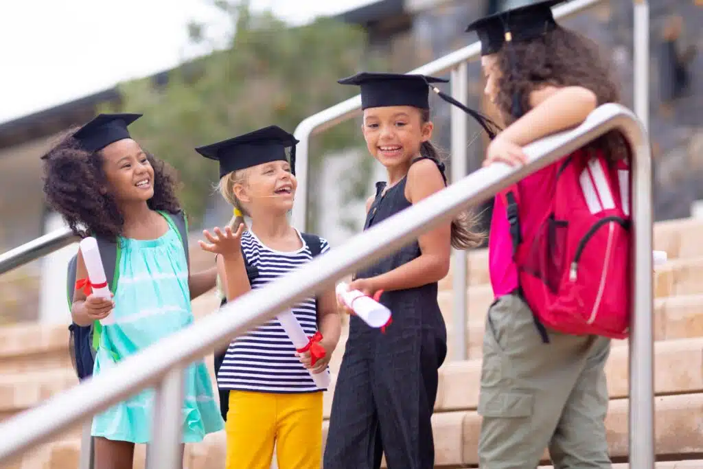 Children wearing university caps on a staircase