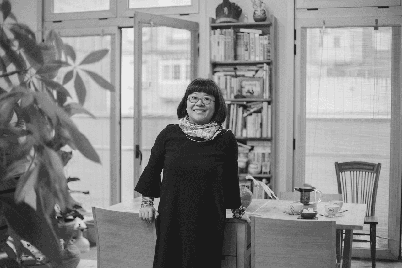 A woman observes framed black-and-white photographs in warm golden light