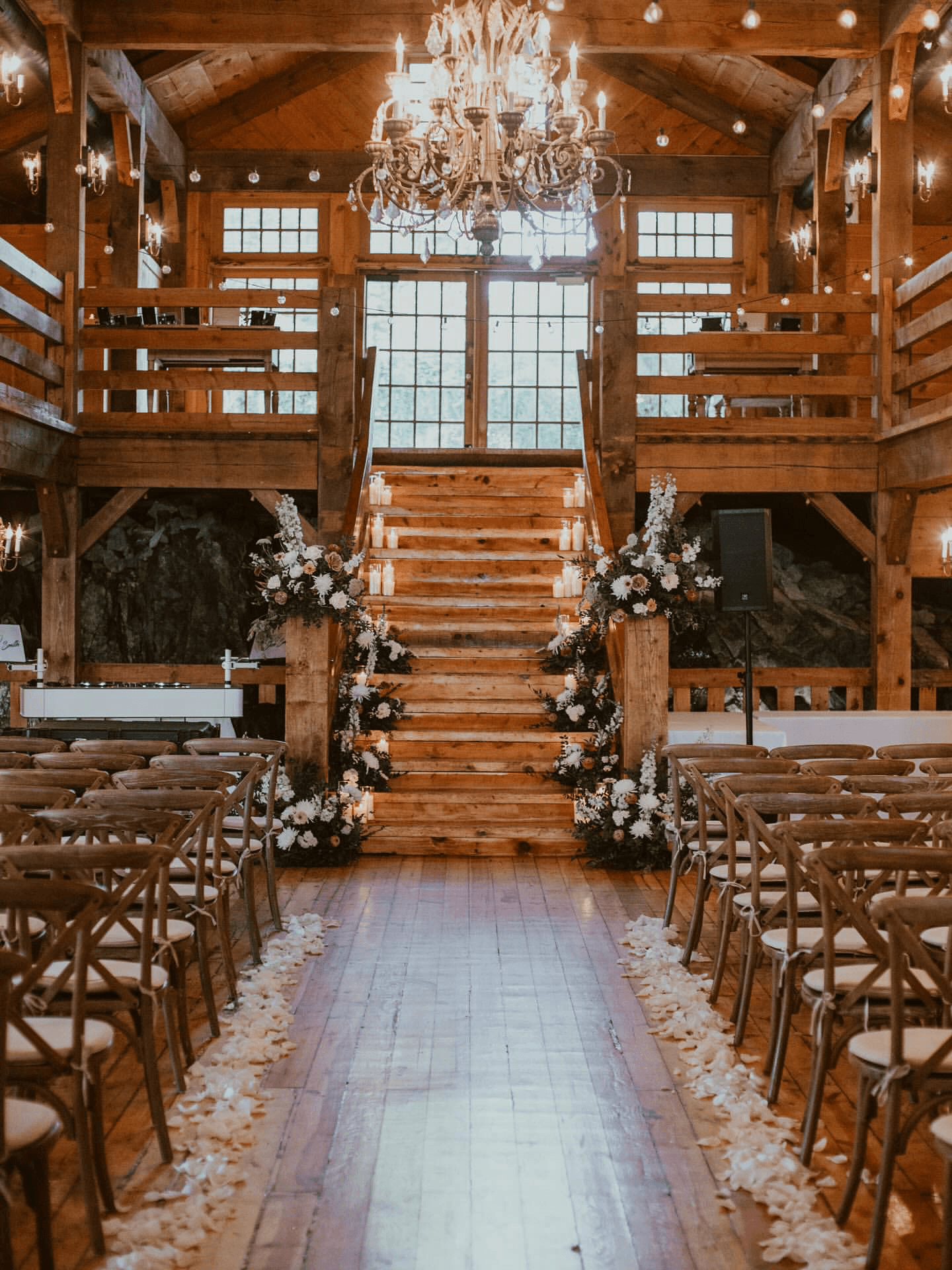 A serene outdoor wedding setup with white chairs arranged on green grass under a canopy of trees.