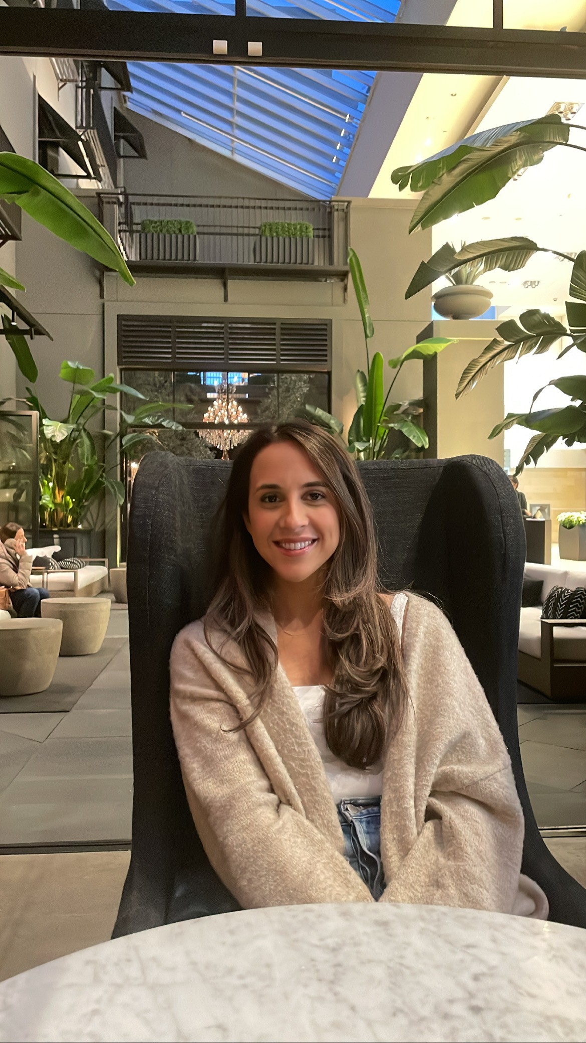 Young woman with long brown hair sits at a table in a restaurant 
