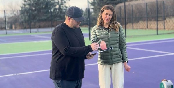Tennis court renovation consultation with facility staff reviewing court conditions.
