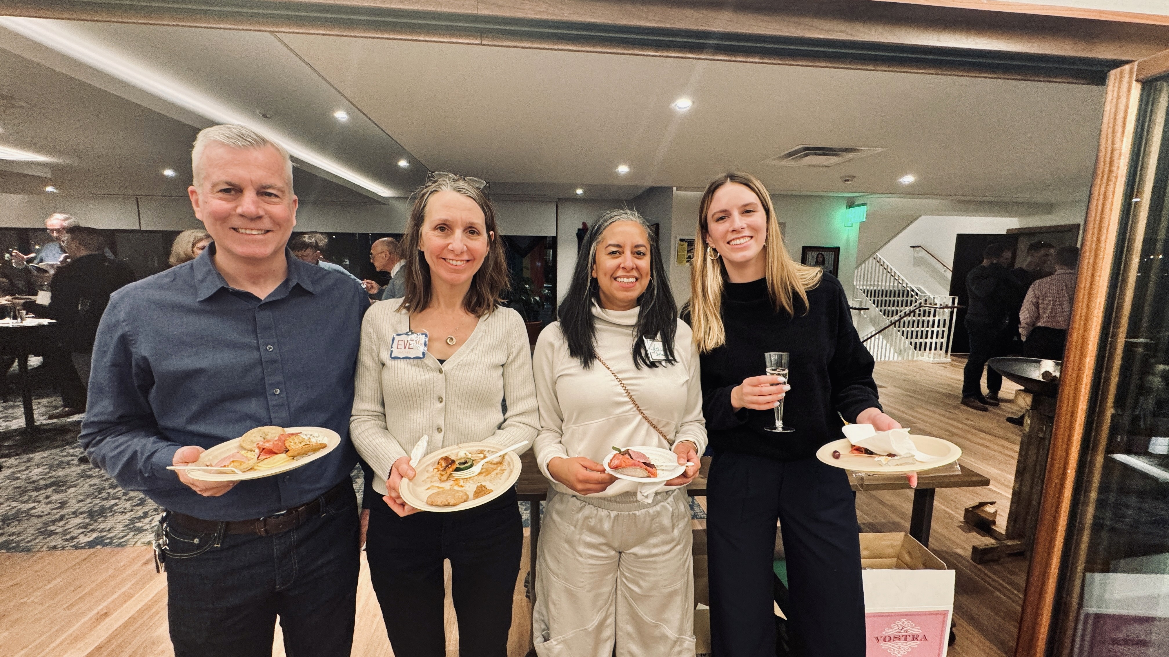 Four Grace Trinity Church members holding plates of food, smiling during a social event.