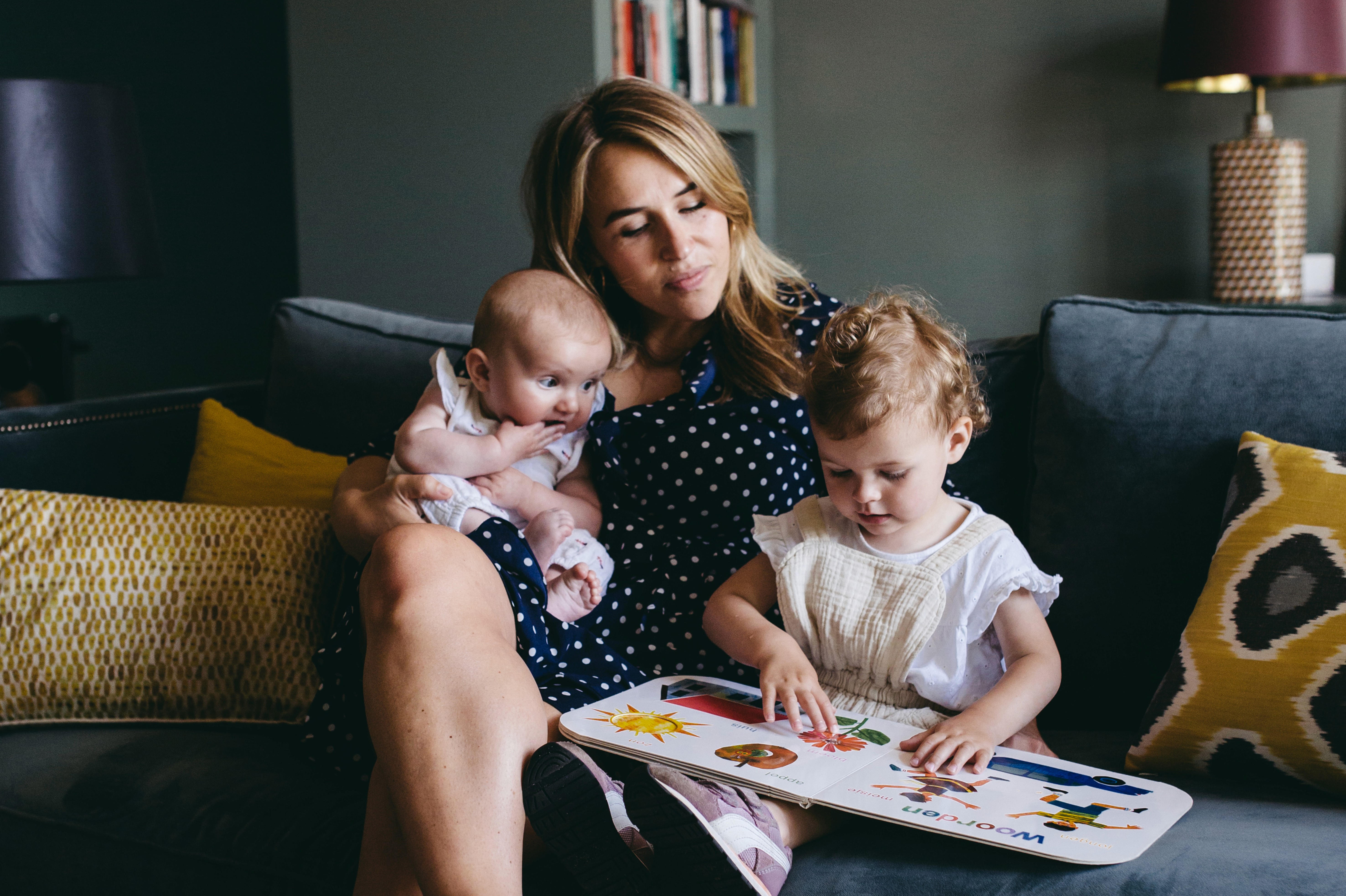 Babysitter reads a book with the children on the couch