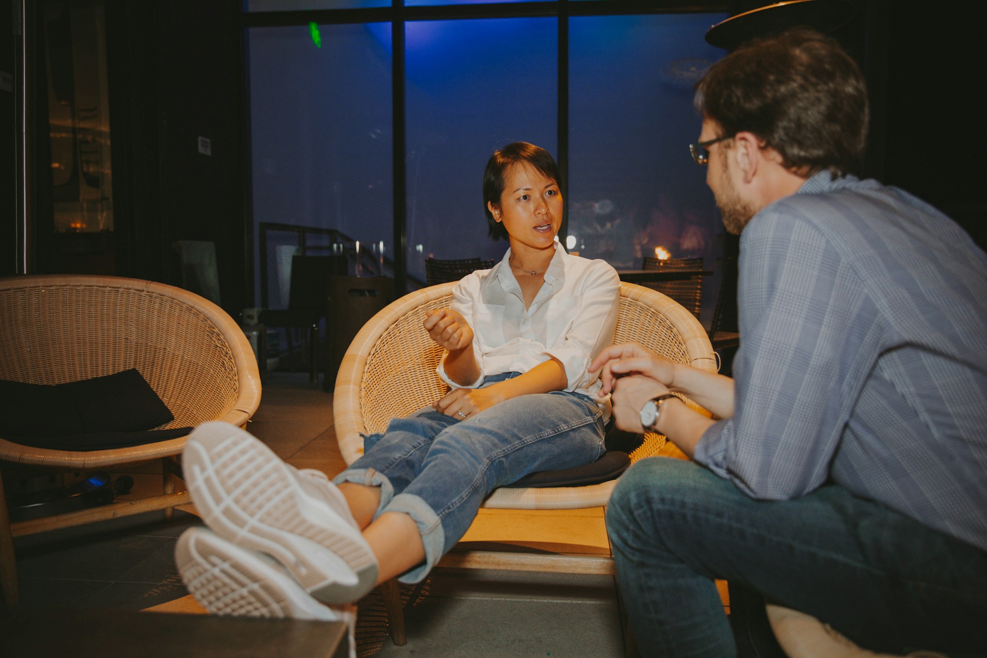 Two members talking in wicker lounge chairs in the evening
