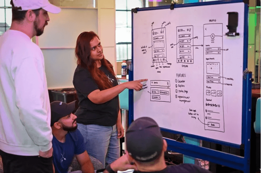 Modern home office setup with a monitor, ergonomic chair, keyboard, and indoor plants near a window with blinds.