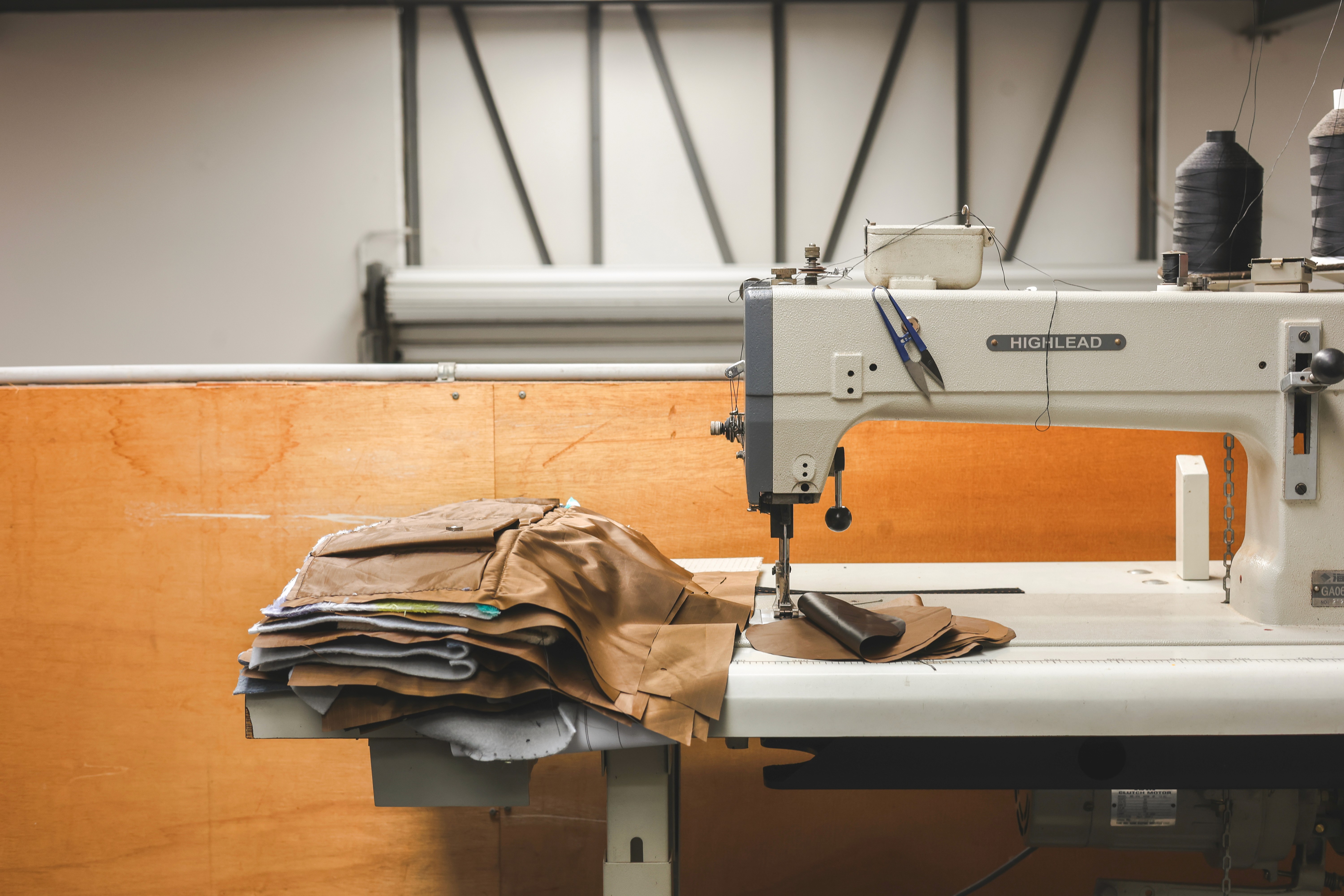Industrial sewing machine beside stacked textile offcuts, ready for upcycling into technical products.