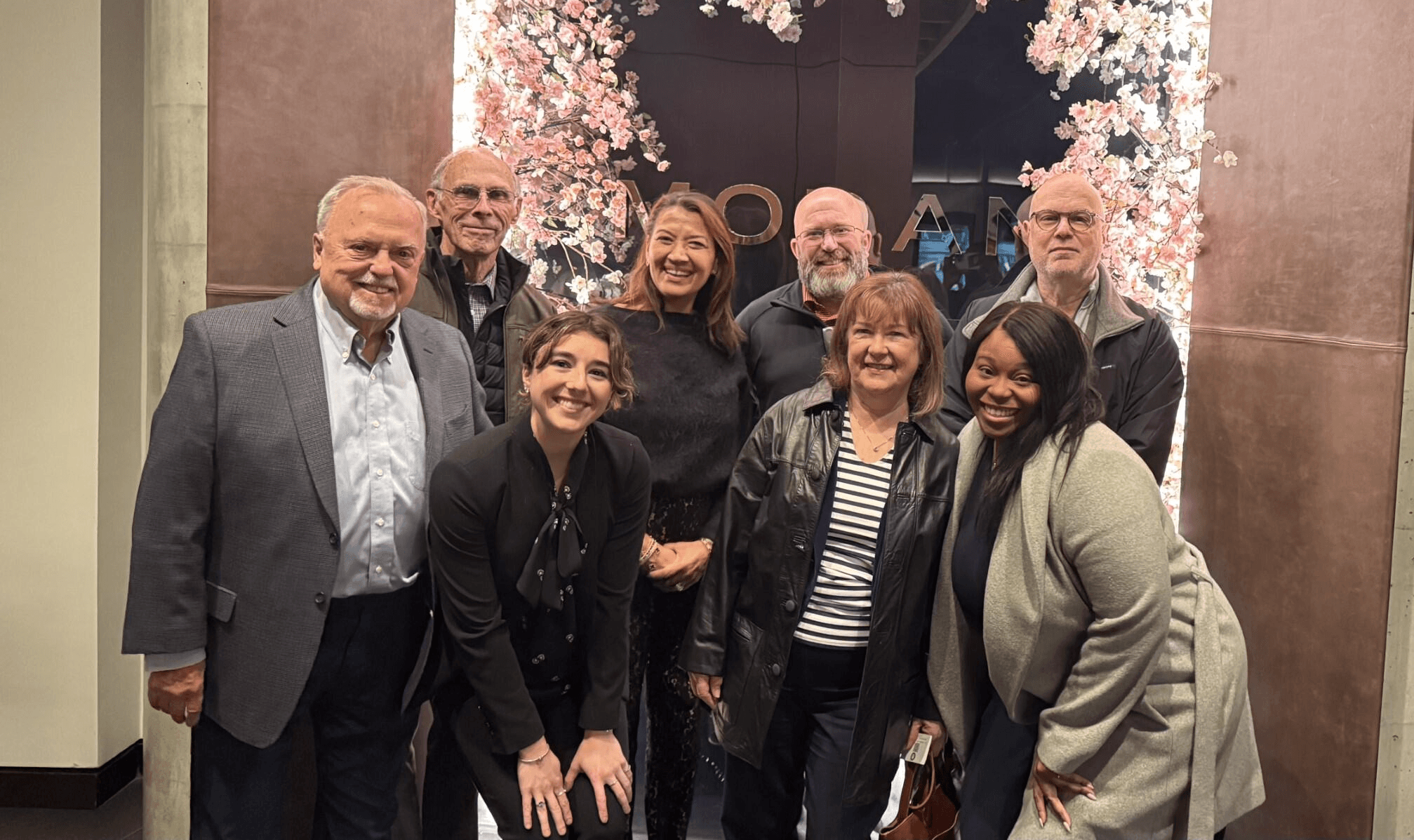 A person points at a computer monitor displaying a colorful graphic design in a modern workspace.