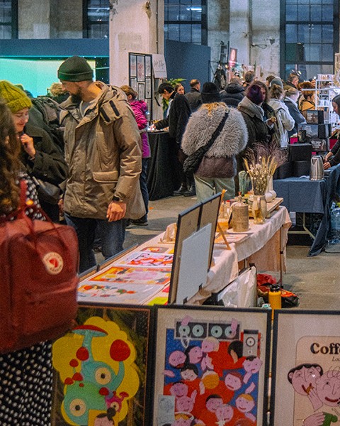 Zdjęcie przedstawiające duża grupę ludzi, którzy oglądają dzieła na stanowiskach targowych.