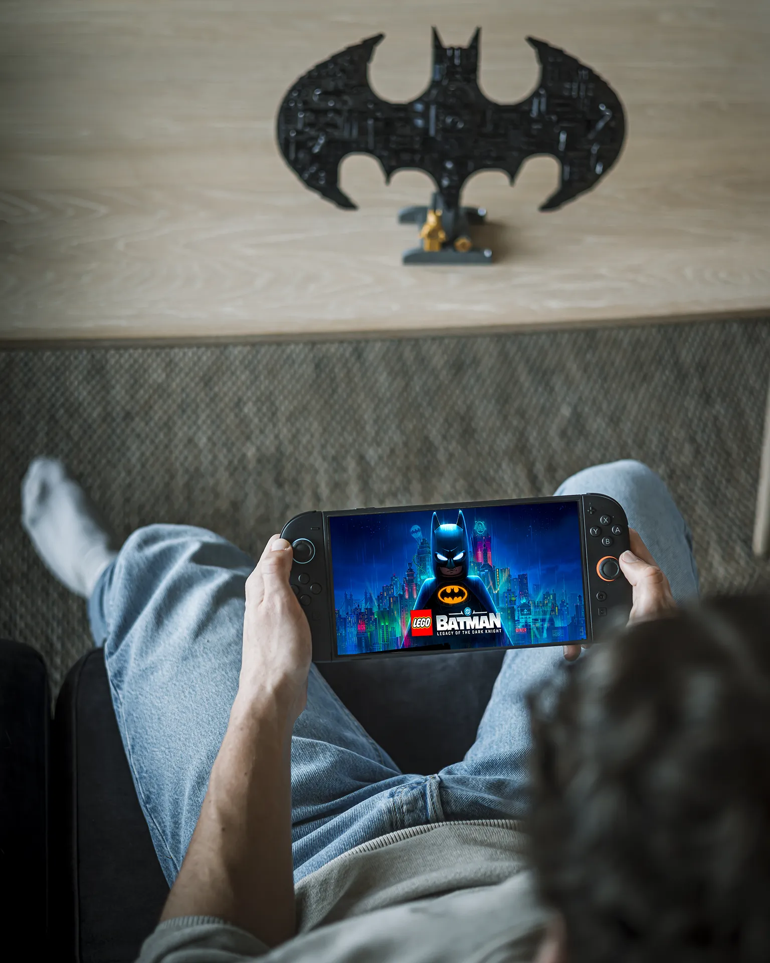 Person spiller LEGO® Batman på håndholdt spillkonsoll