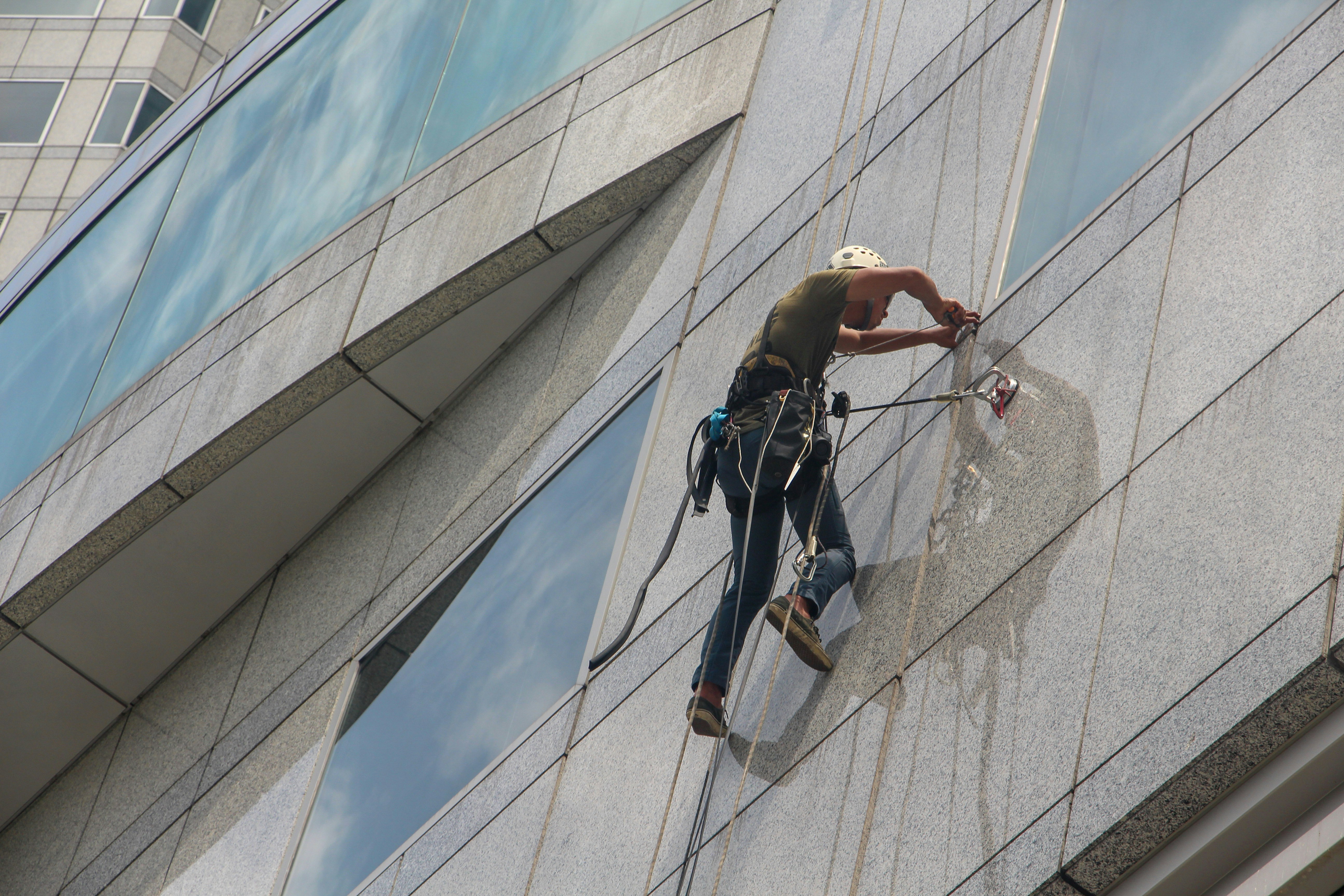 A person cleaning wall and window in the air