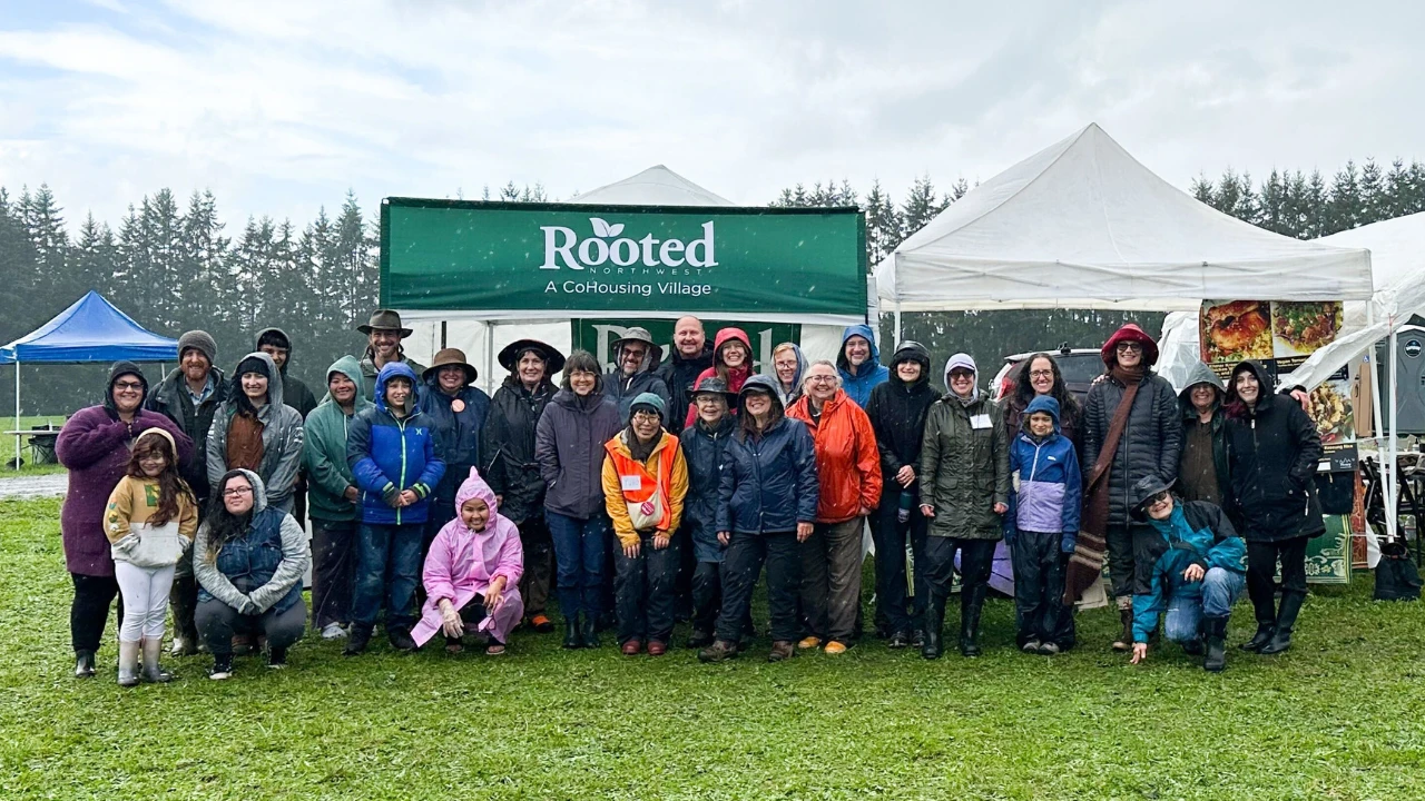 Group of community members standing together in the rain beneath a Rooted Northwest tent at Fall Farm Fest.