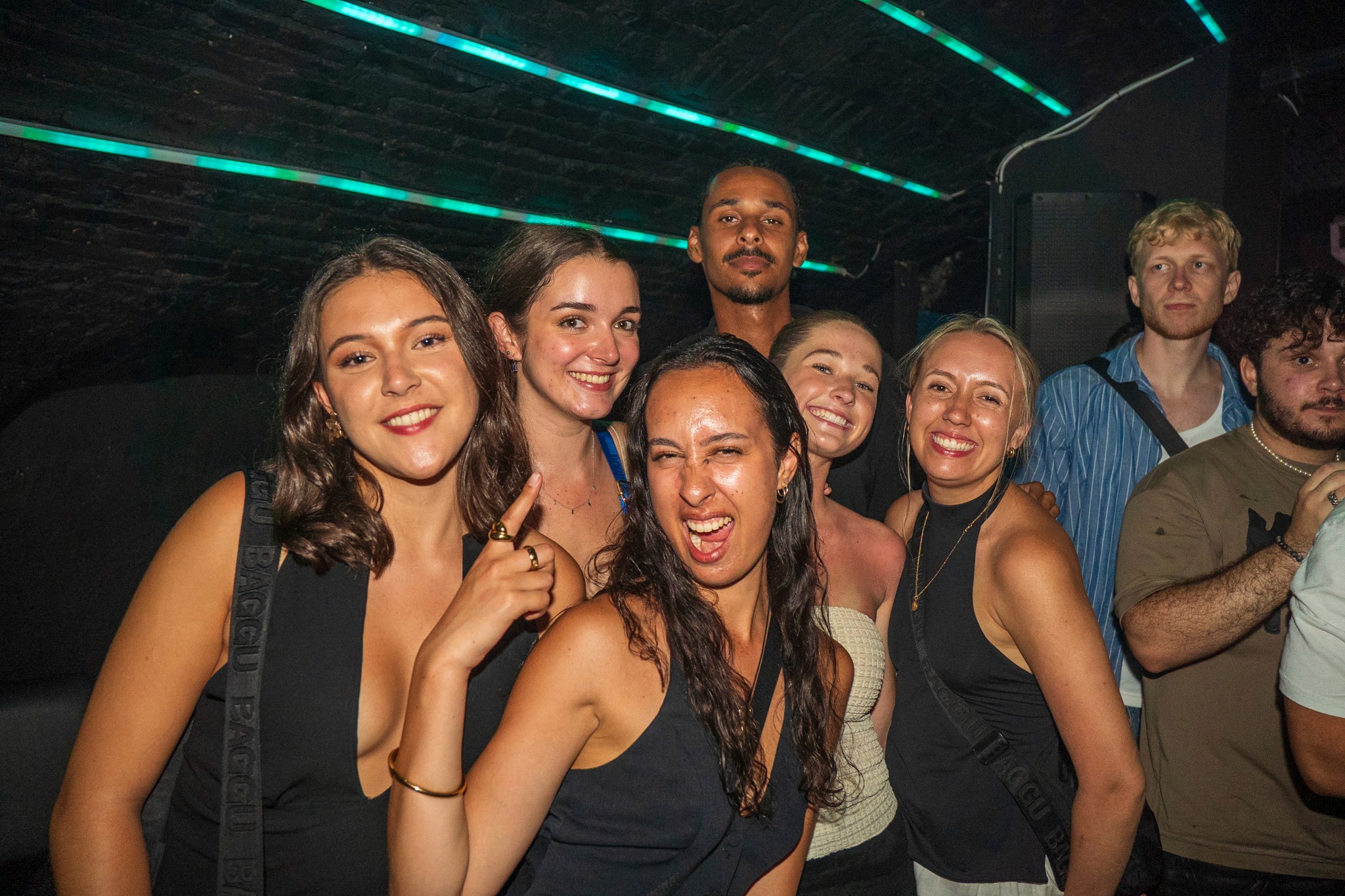 Group of young travelers smiling and celebrating inside a packed underground club during a bar crawl in Nice showing strong group energy nightlife excitement social connection and the high intensity party atmosphere typical of the French Riviera nightlife experience