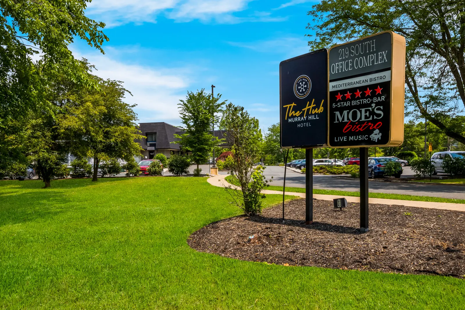 Sign for The Hub Murray Hill Hotel and Moe's Bistro next to a green lawn.