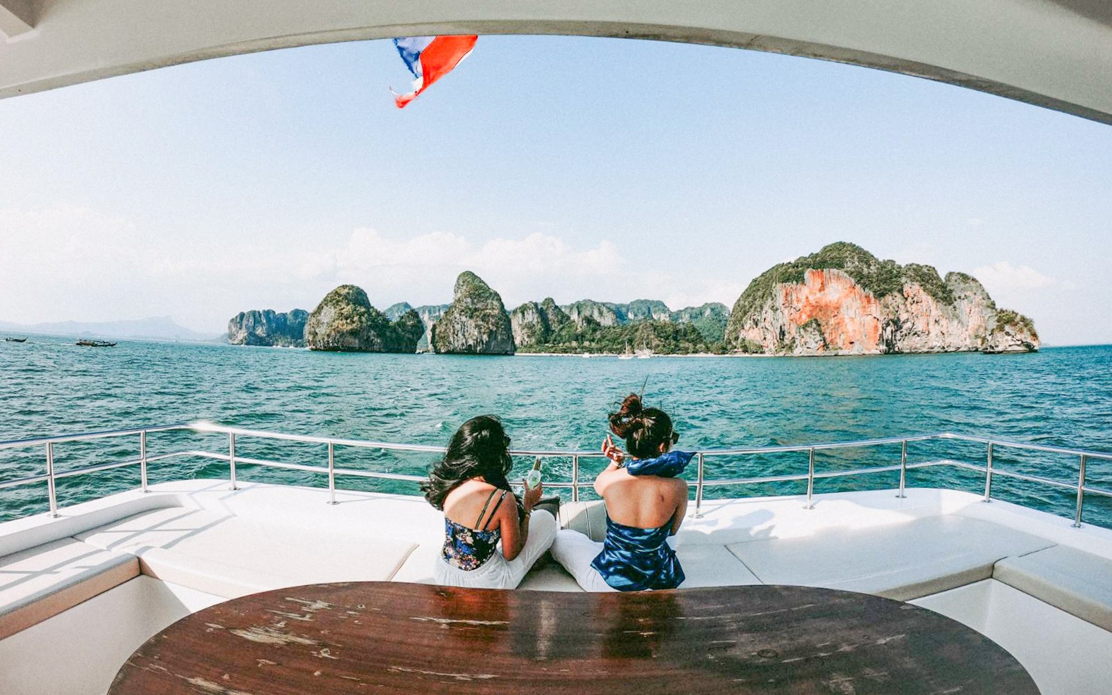 Tourists on a yacht enjoying views of limestone cliffs in Phang Nga Bay, Phuket.