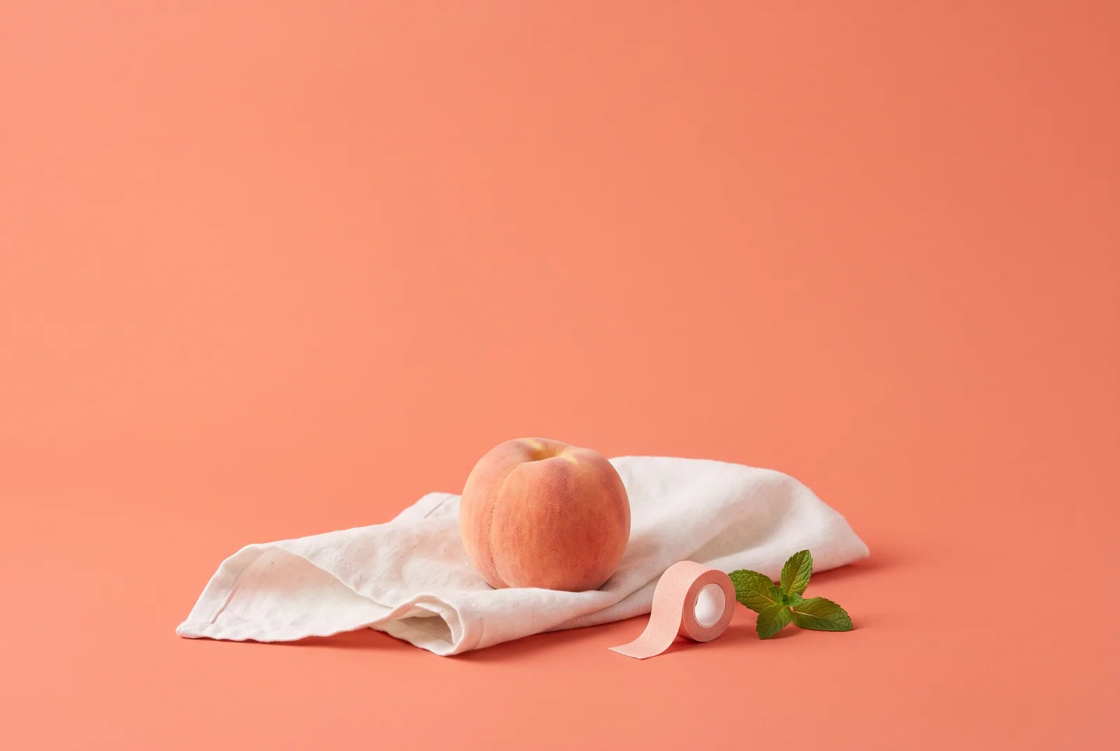 A peach on a soft linen napkin beside bandage tape and mint, how to heal from betrayal trauma