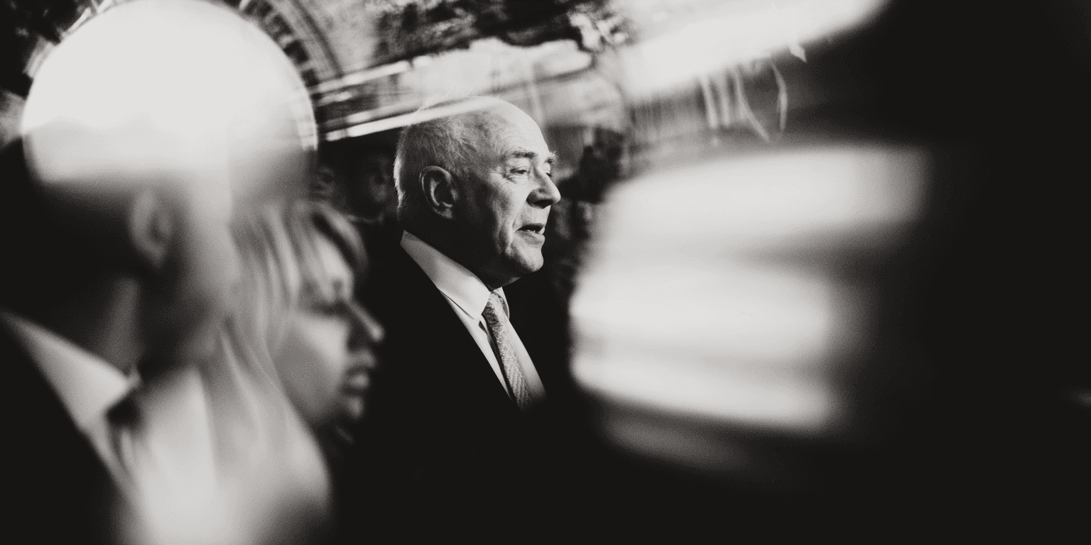 The image captures a dynamic, high-contrast moment of a basketball player in mid-air against a plain bright background.