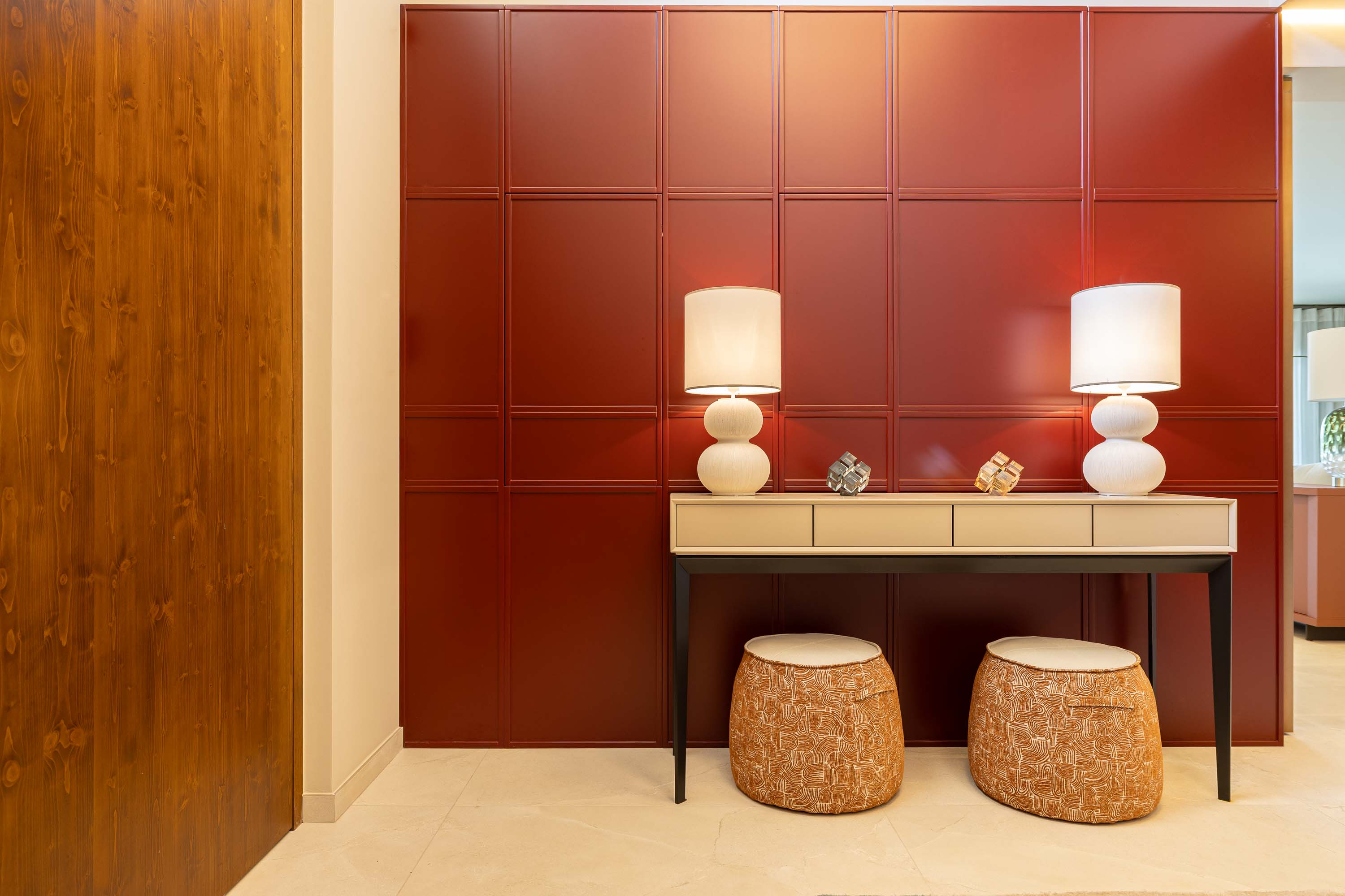 Red panelled entrance hall with a cream console, sculptural white lamps and woven stools, in a Vale do Lobo home