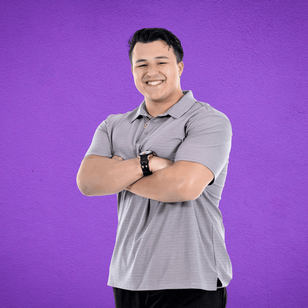 a man standing in front of a purple background with his arms crossed
