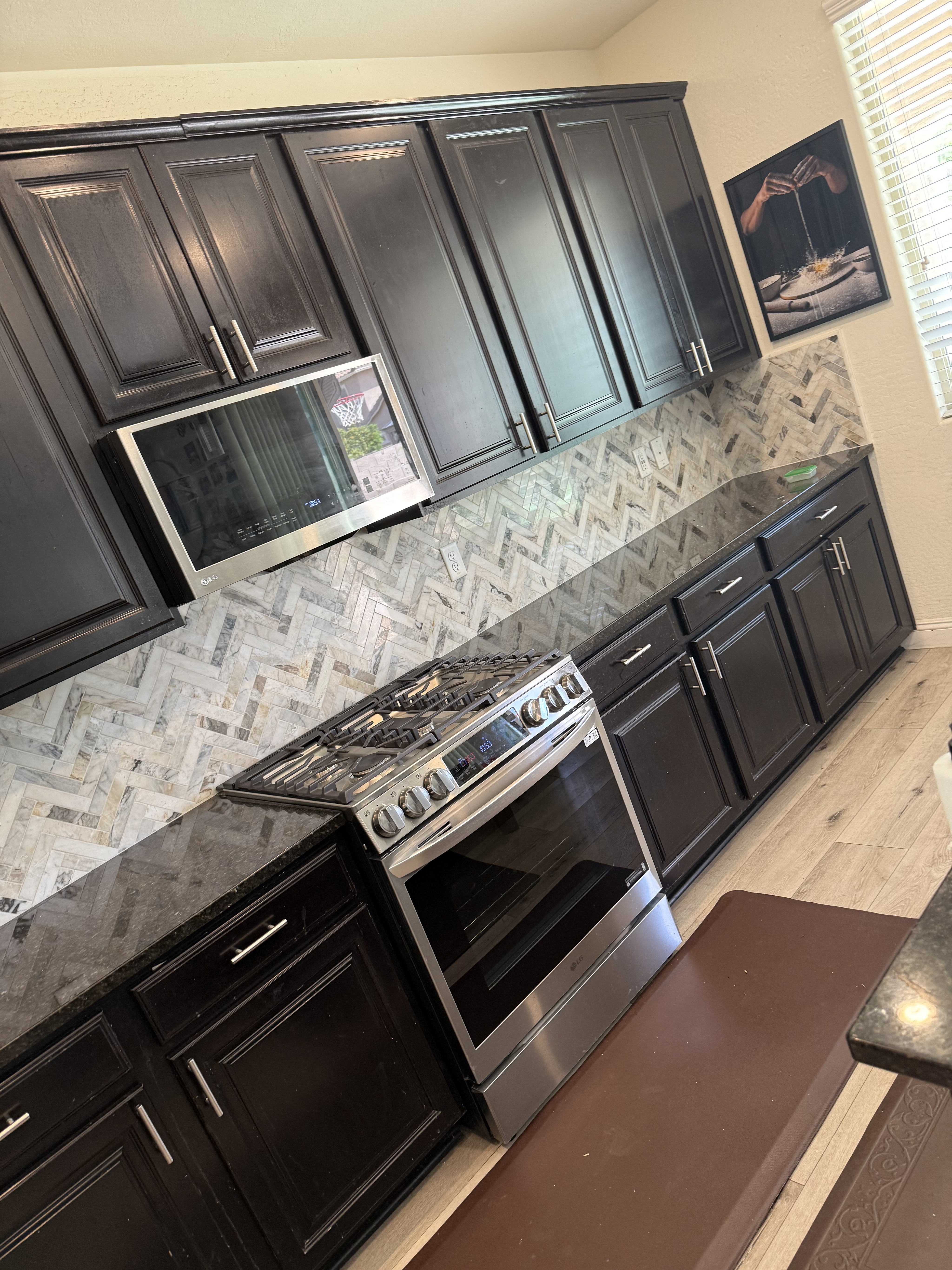 Modern kitchen with a stainless steel range hood and a dark tile backsplash under construction with spacers.