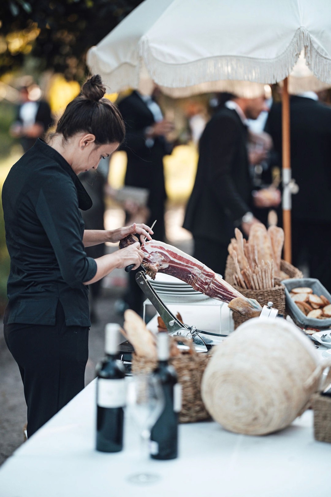 Crisp Catering Ibiza staff slicing jamón ibérico at an outdoor wedding charcuterie station.