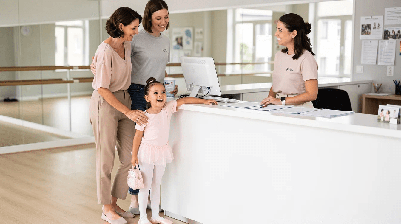 A joyful family stands at a dance studio reception desk, with a child in a colorful dance outfit displaying excitement. The scene captures the essence of class registration, highlighting the importance of user-friendly registration software solutions for educational institutions.