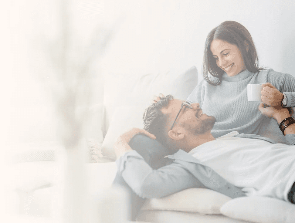 Woman smiling and her partner sitting on the couch representing Flouria’s fertility care