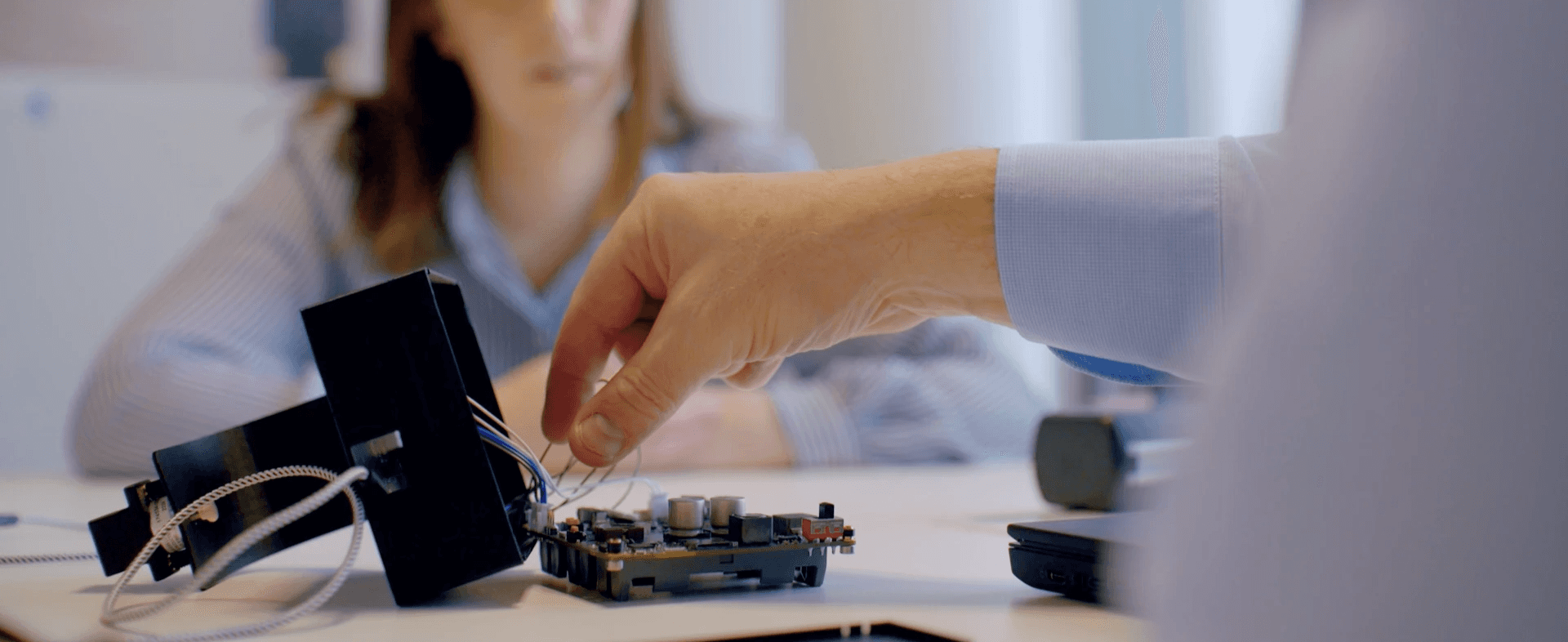 CPI expert's hand pointing to a specific part of a MedTech device, in conversation with a client.