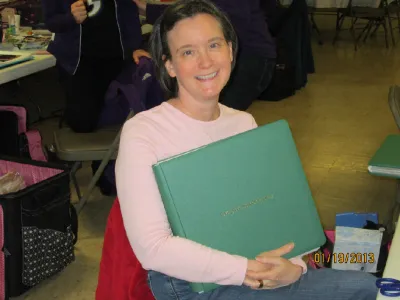 Woman holding a green scrapbook album on her lap