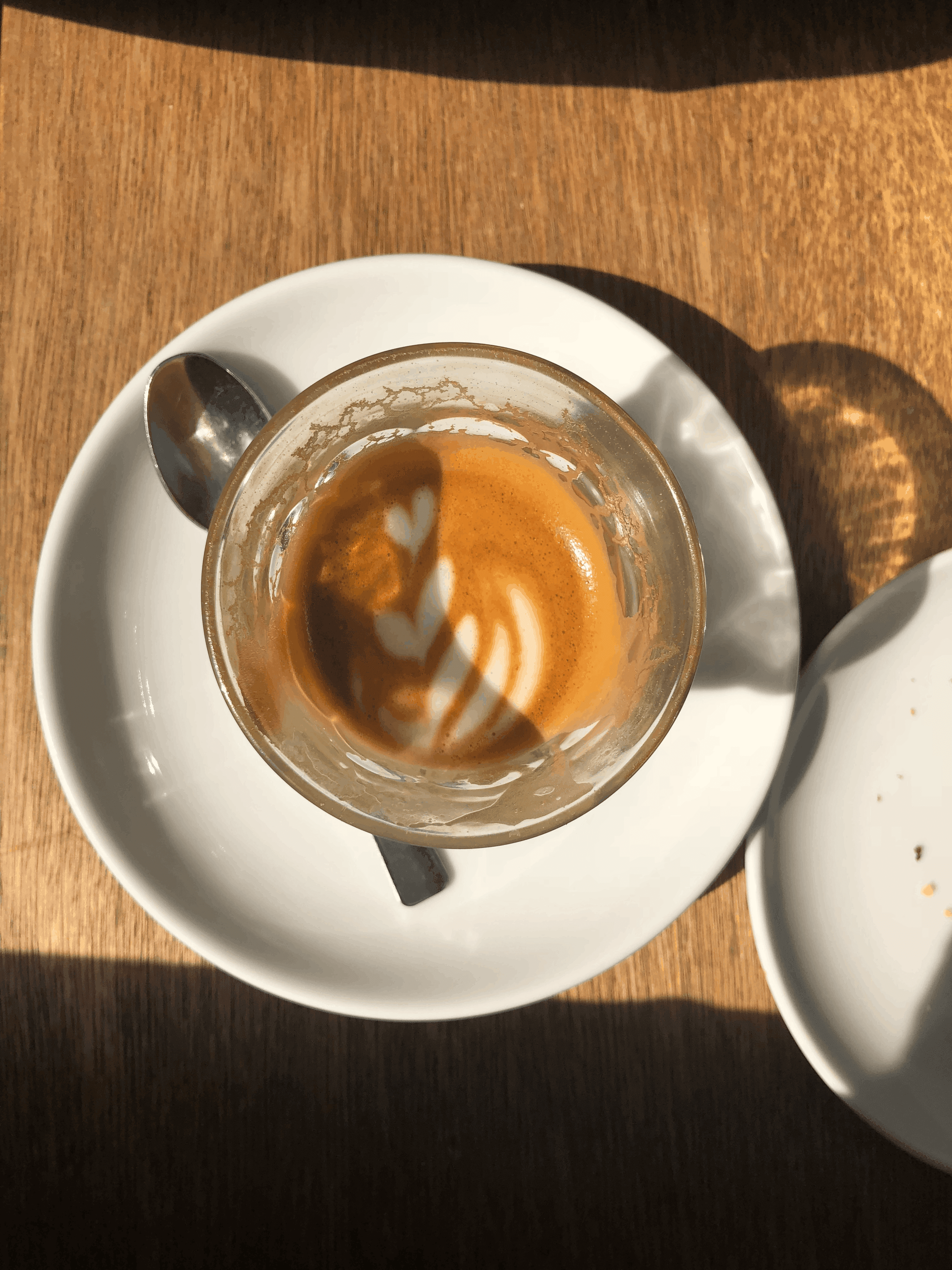 Overhead view of a half drank cortado and it's remaining latte art in a glass on a white saucer