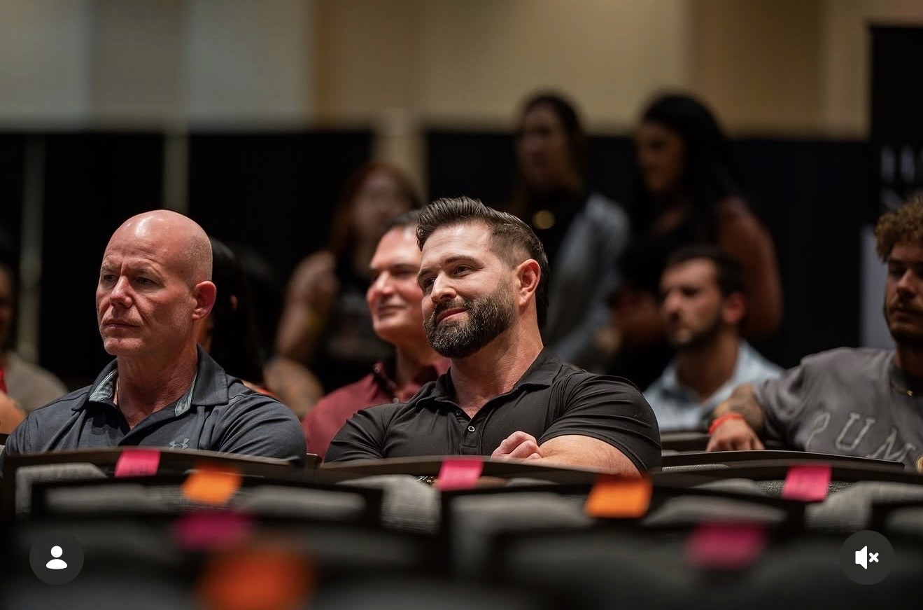 Coach Chase Gloeckner supporting a Chasing Gains client on stage at a bodybuilding competition