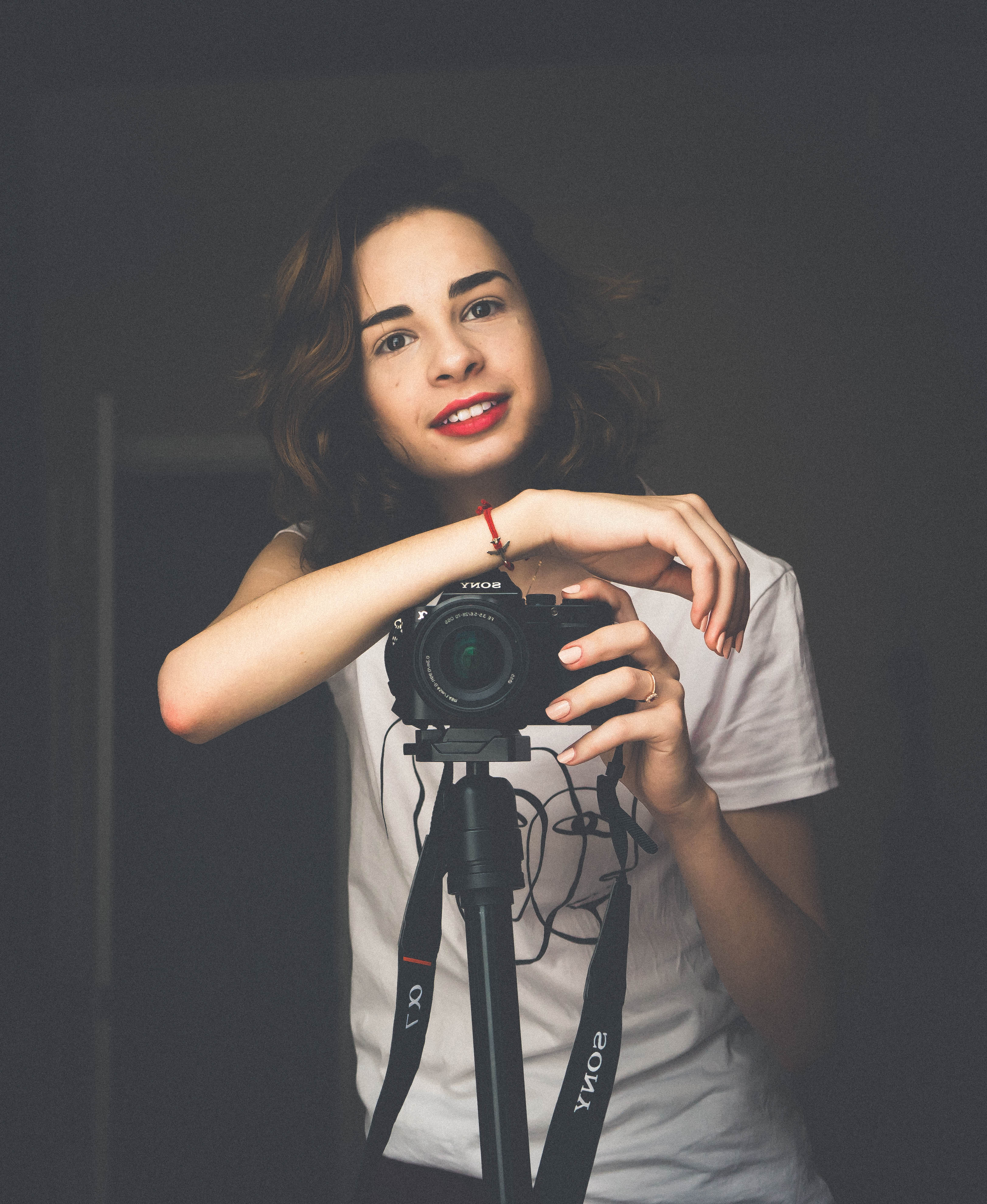 A person with shoulder-length blonde hair wearing a black newsboy cap and a black sweater.