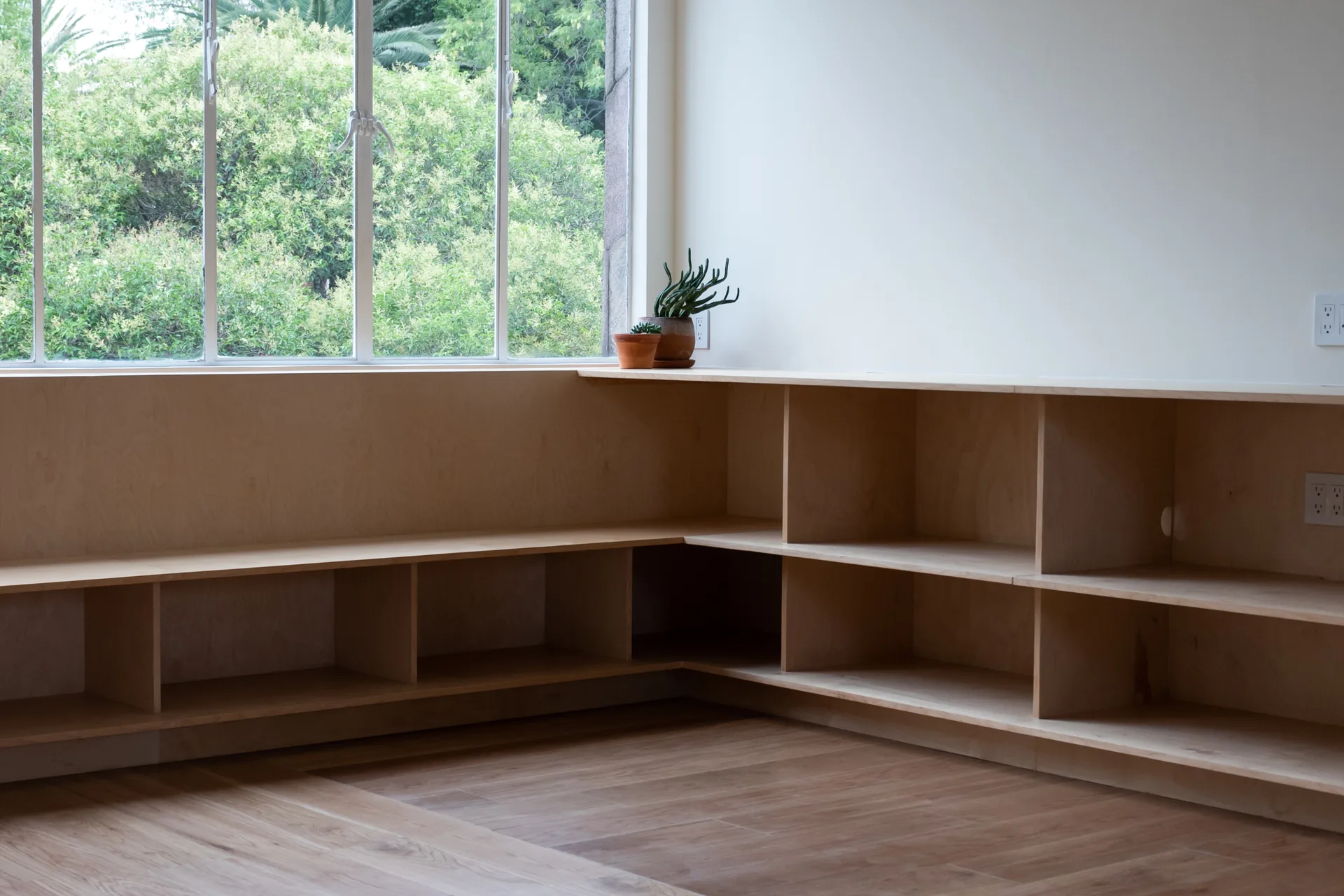 Mueble bajo de madera en esquina bajo la ventana, con planta