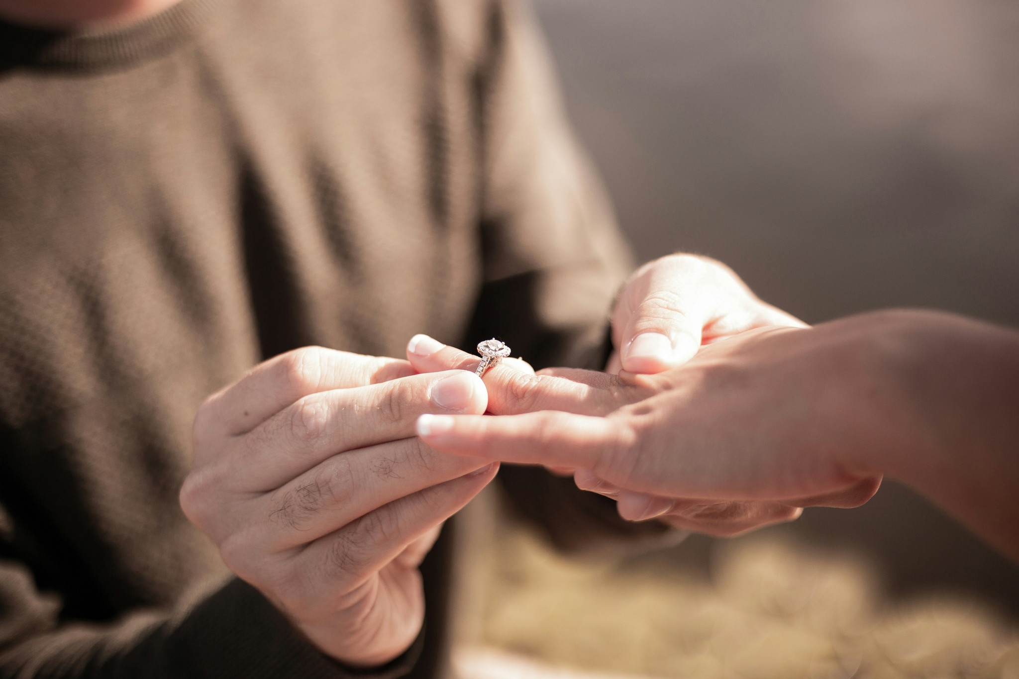 Couple exchanging a solitaire engagement ring during an outdoor proposal at golden hour