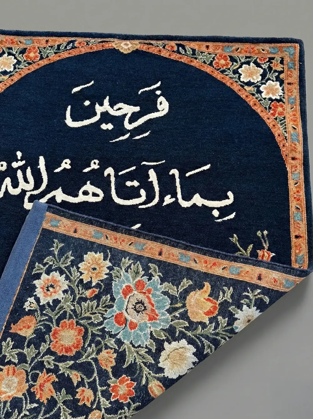 Detail of a hand-knotted wool carpet with Arabic calligraphy and a floral border