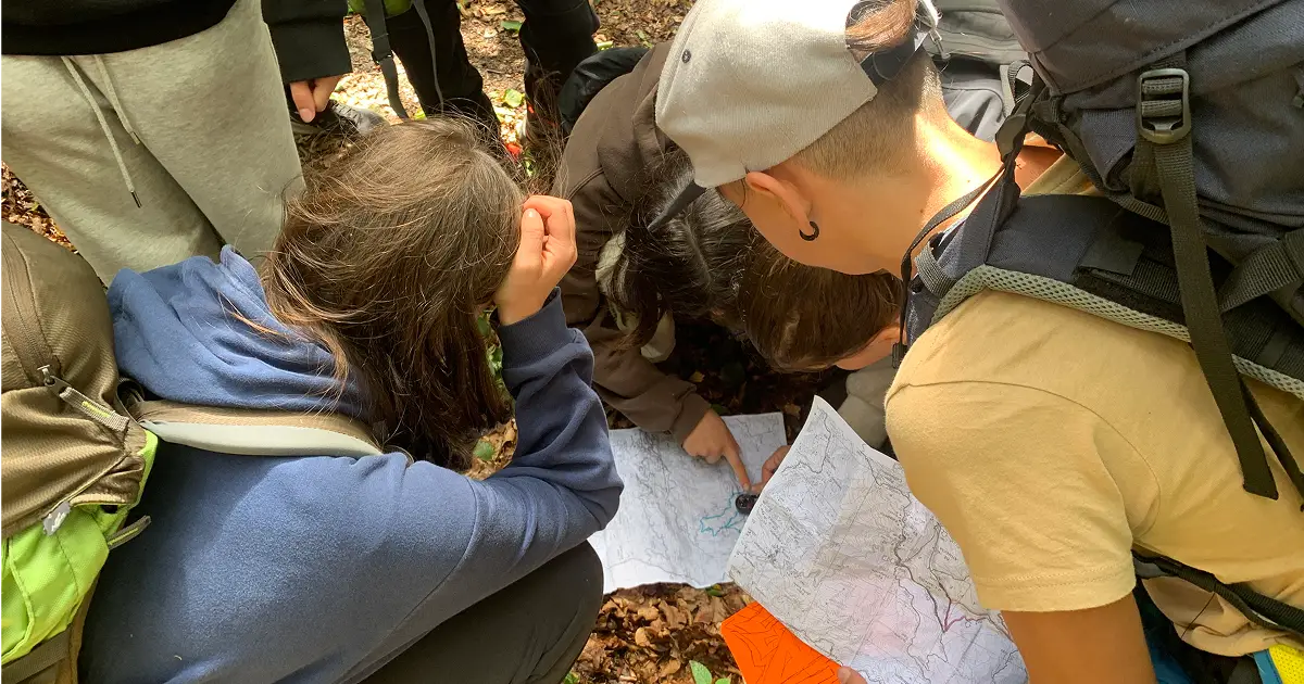 ragazzi e bambini che studiano un percorso in orienteering nella foresta
