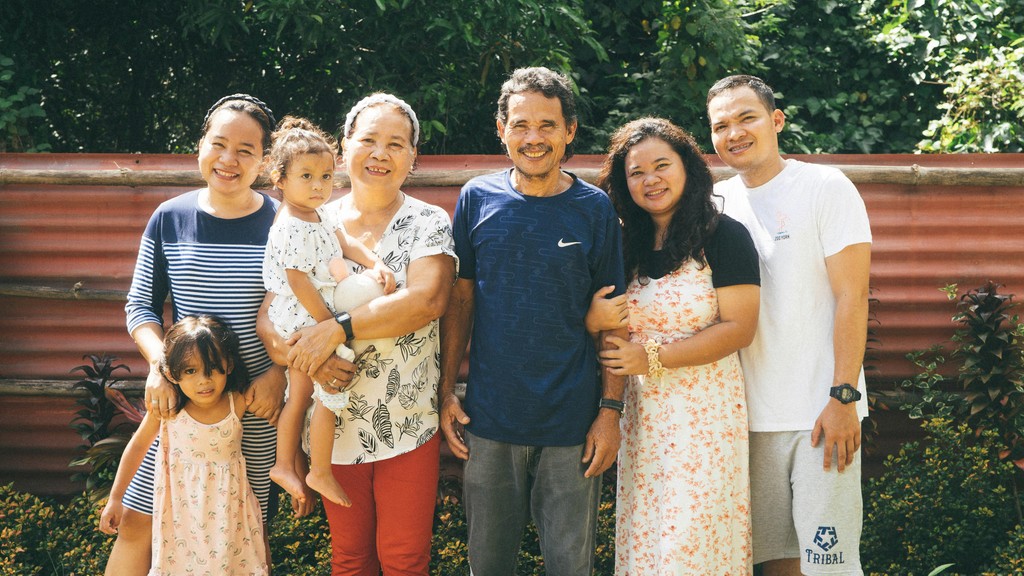 A smiling multi-generational family including grandparents, adult children, and grandchildren standing together outdoors, representing successful family reunification through the Canadian Super Visa program.