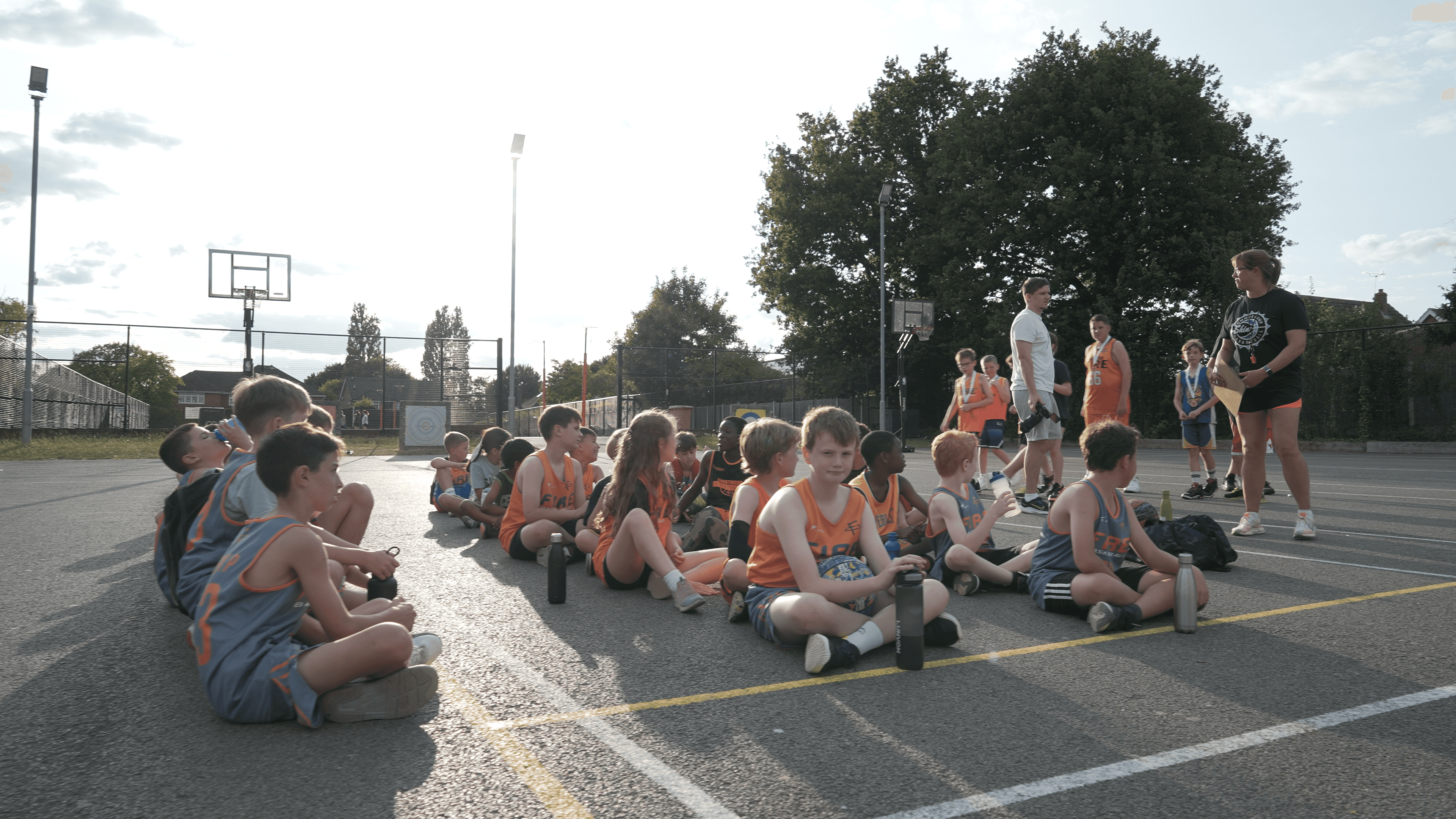 Kids in bibs sitting together on basketball court