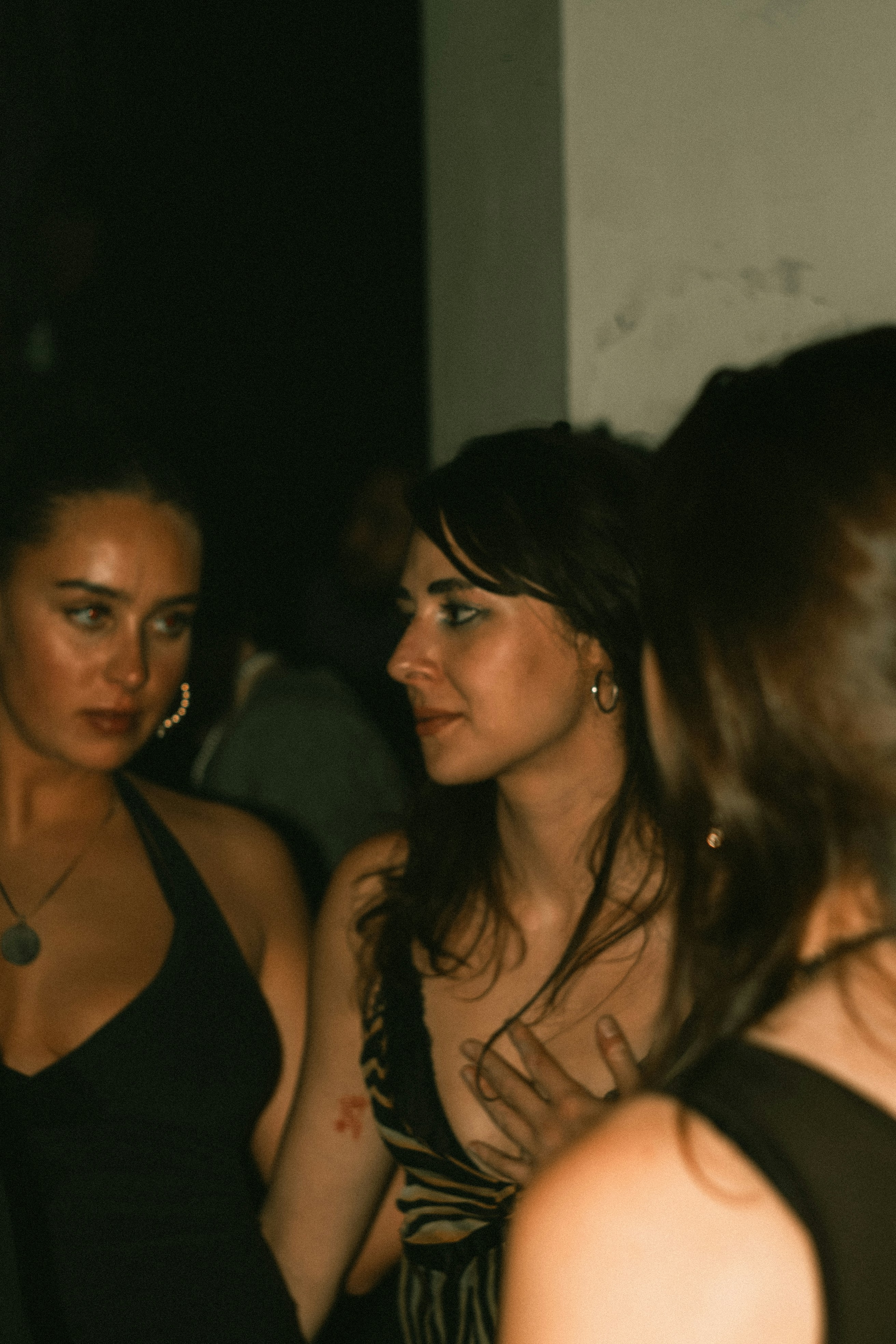 Three women in dark dresses at a social gathering.