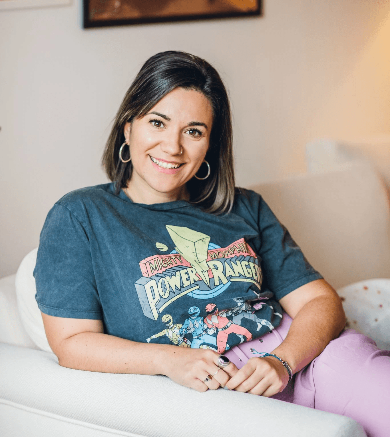 A confident person with short, styled hair and a leather jacket poses against a dark backdrop.