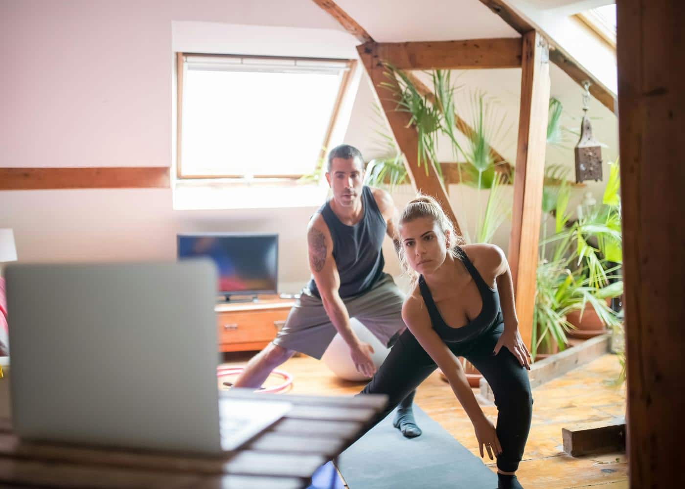 Man and woman working out indoors while looking at an open laptop