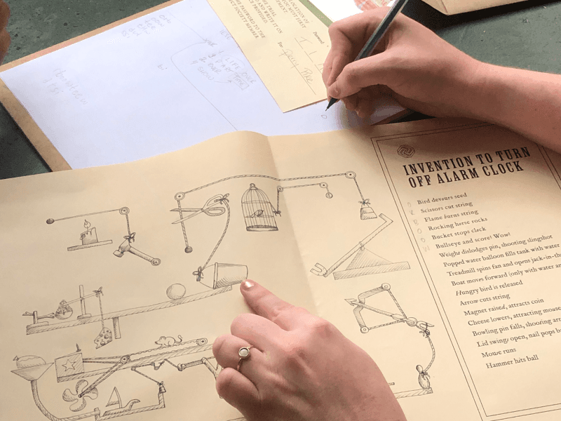 Hands examining a strange diagram on a piece of parchment.