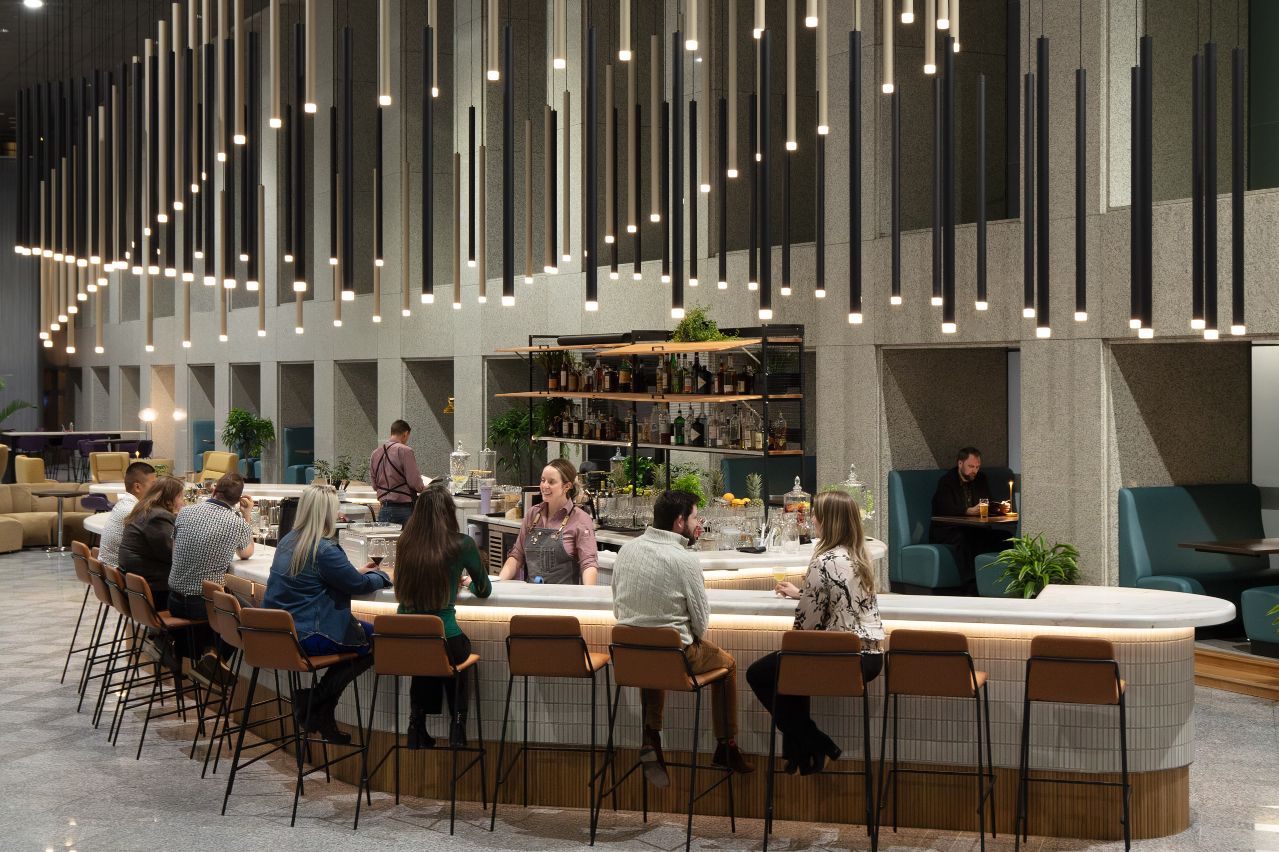 Modern bar with pendant lights and patrons seated.