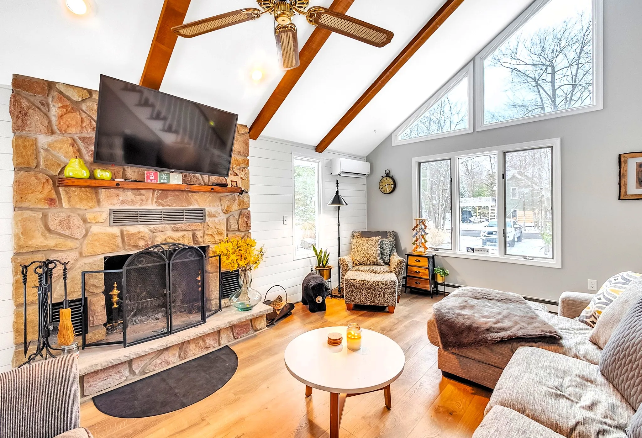 Living room with stone fireplace, wall TV and round coffee table at Beechwood Bliss