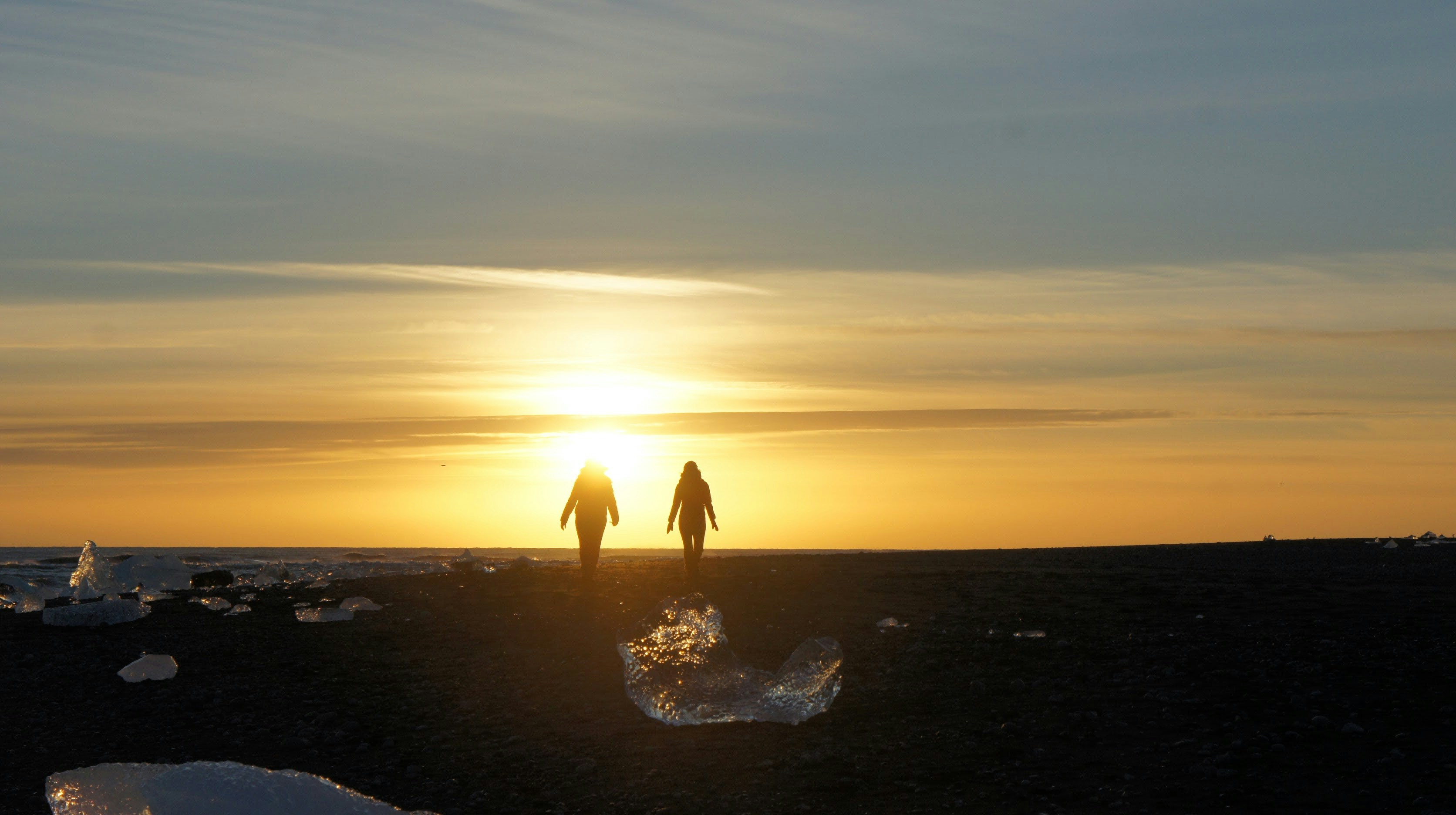 Silhouette of a couple walking along Diamond Beach in Iceland.