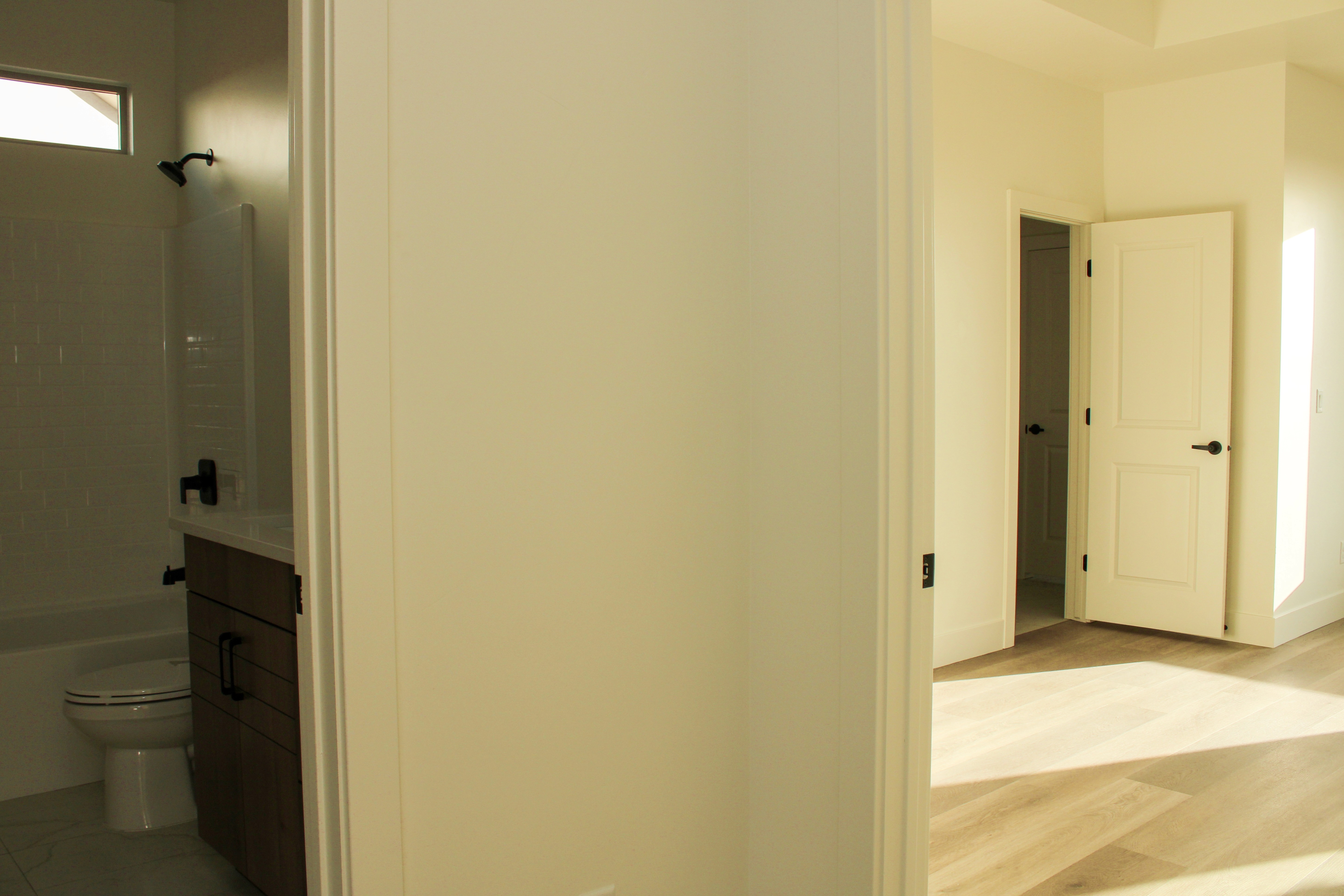 Hall bathroom area inside the Golden Hour home in Hurricane, Utah with a view down the hallway toward the primary bedroom.