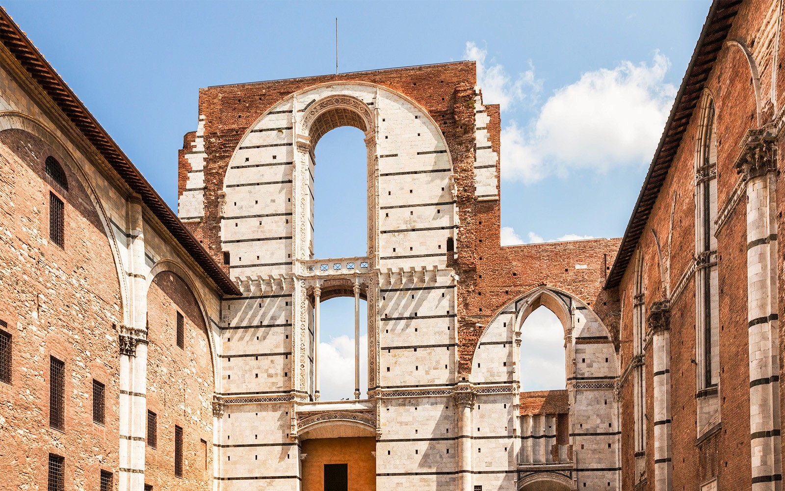 Siena Cathedral Complex facade with arches and brick walls, Italy.