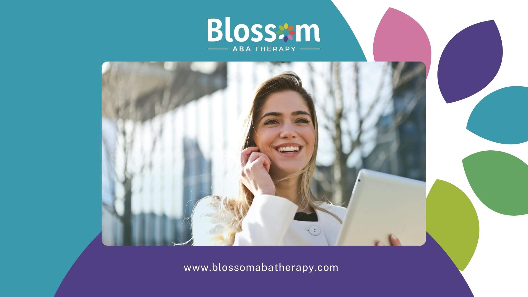 Female ABA therapist in white coat smiles outdoors, holding tablet and touching ear in urban setting.