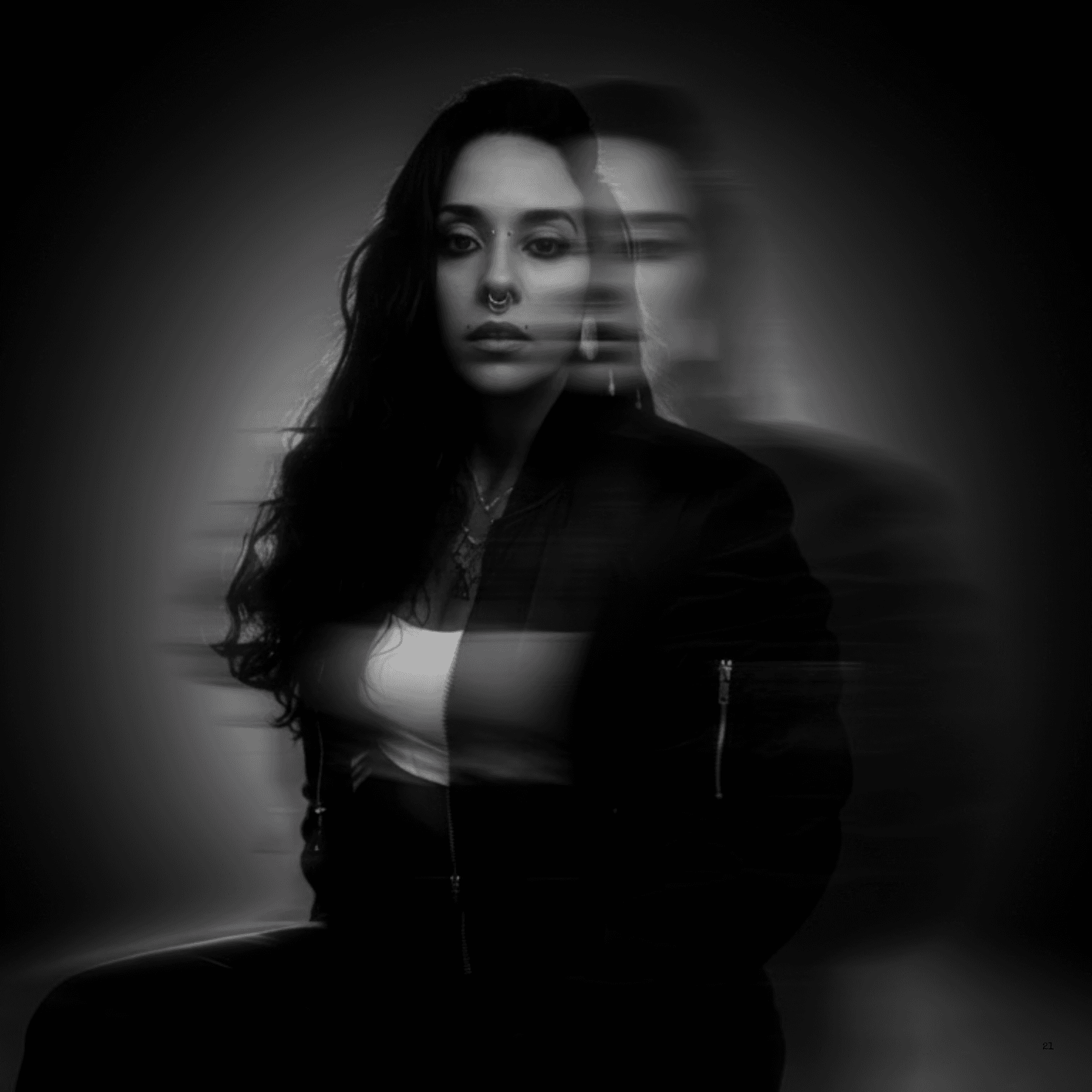 A thoughtful young person with dark hair gazes to the side, captured in soft black and white lighting.