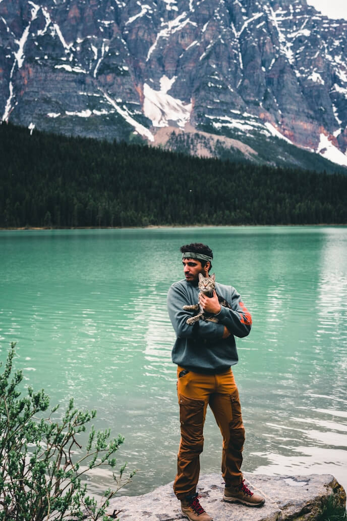 A boy is holding a cat in his arms in the nature.