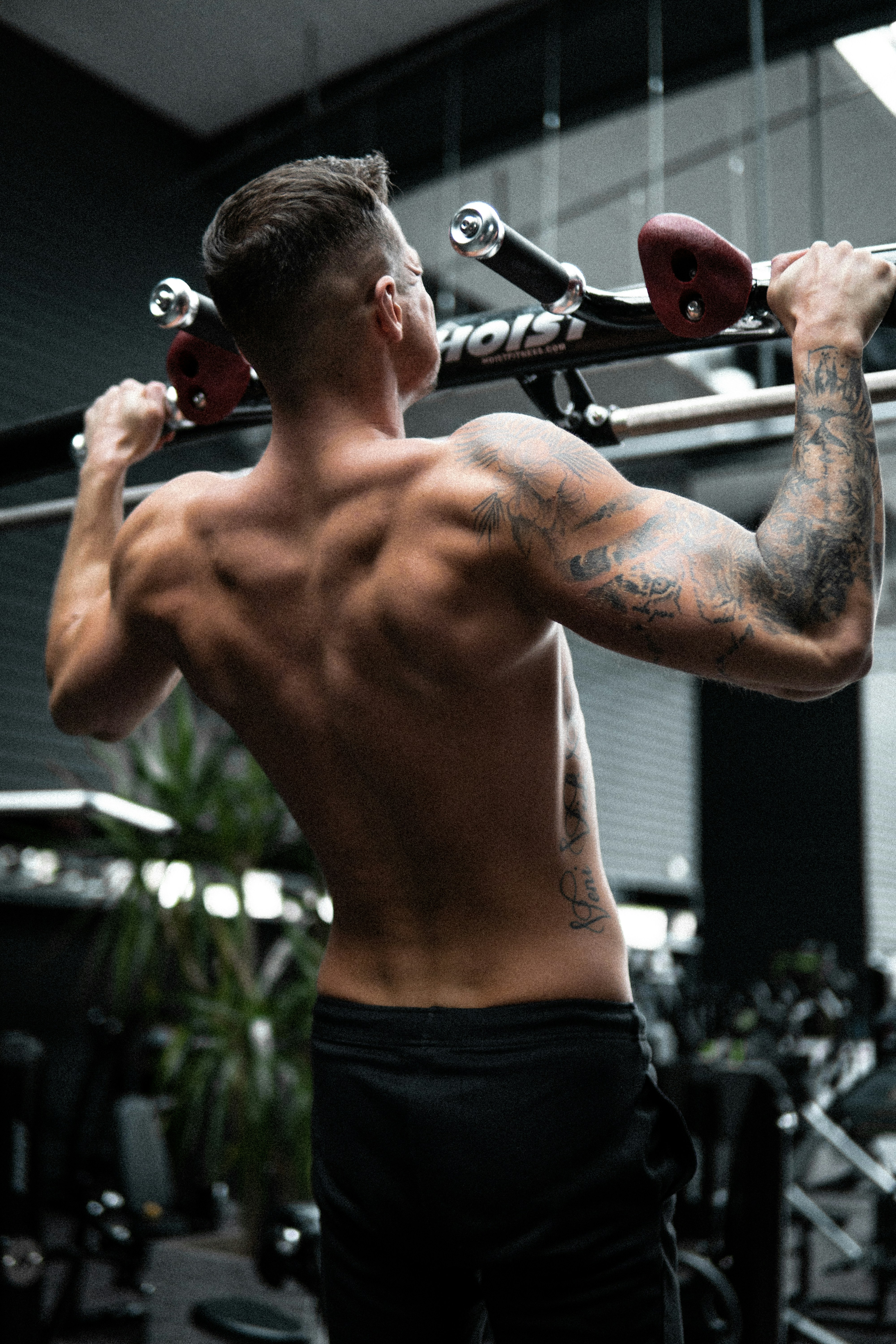 topless man in black shorts holding red and black kettle bell